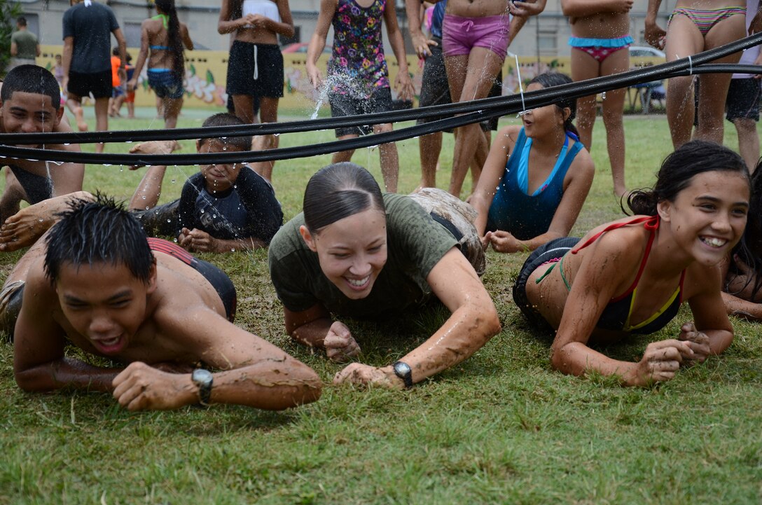 Cpl. Geomary Diaz, administrative clerk, Manpower, Personnel and Administration (center), low-crawls at the water limbo station with sixth graders Reggaen Eugenio and Artaysia Hashimoto during Kailua Elementary School’s Ho Ike picnic and water play day on campus, May 17, 2013. (U.S. Marine Corps photo by Kristen Wong)