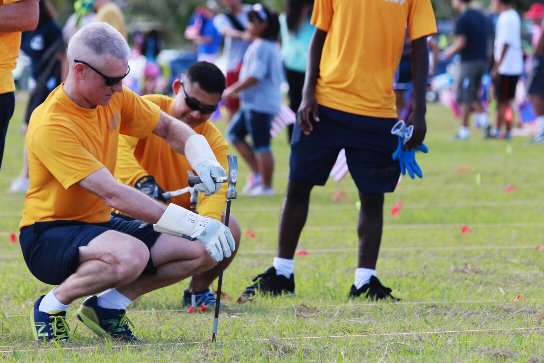 Commander Doug King, Naval Facilities operations officer and native of Rockford, Illinois, hammers in rebar to create holes for building a flag display for Memorial Day, May 25, 2013, Asan Beach, Guam.  Marines, Sailors, Airmen and Army National Guardsmen participated with local volunteers and the National Park Service to commemorate Memorial Day by honoring service members and civilians who died in the Japanese invasion, occupation and United States liberation of Guam during World War II.