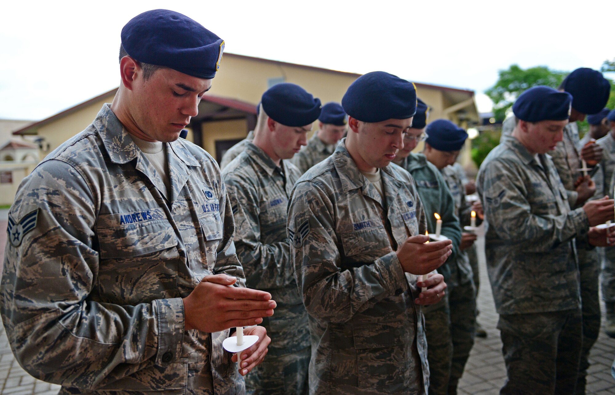 Senior Airman Brandon Andrews and other 31st Security Forces Squadron members bow their heads for prayer during a candlelight vigil for National Police Week May 21, 2013, at Aviano Air Base, Italy. Police week is held annually to honor the contributions and sacrifices of law enforcement officials around the world. (U.S. Air Force photo/Airman 1st Class Matthew Lotz)