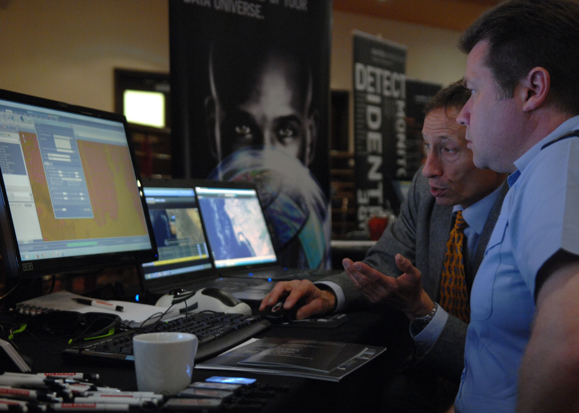 From left, an exhibit presenter explains his display to an attendee during a Technology Expo hosted by the 100th Communications Squadron May 23, 2013, at the Galaxy Club on RAF Mildenhall, England. The exposition showcased multiple types of technology. (U.S. Air Force photo by Airman 1st Class Dillon Johnston/Released)