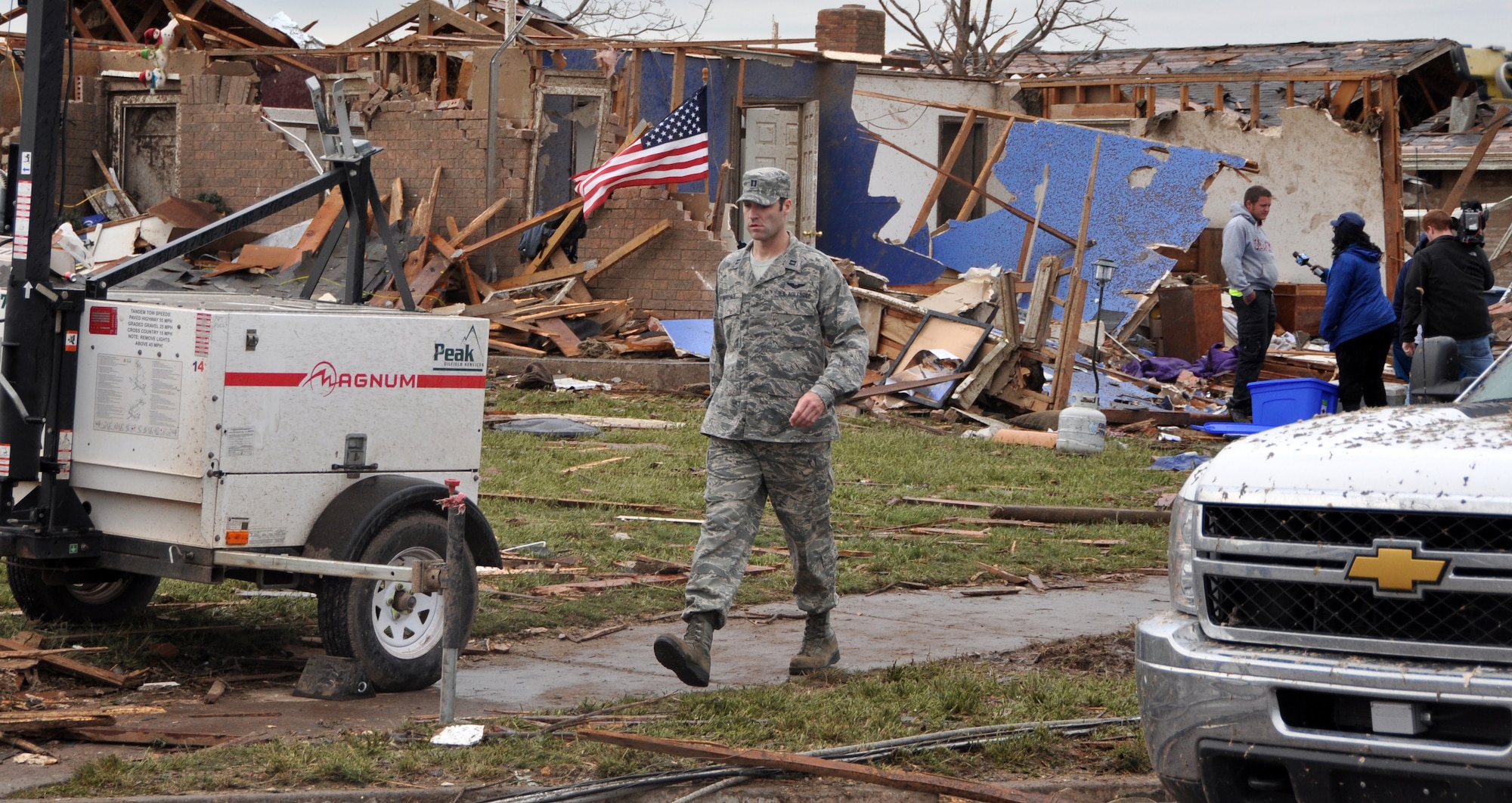 An Air Force member moves through a neighborhood looking for people in need of help in the aftermath of the devastating tornado that ripped through Moore Okla., Monday May 20, 2013.  One of the hundreds of Oklahomans to lose their homes is being interviewed as the Airman watches for downed power lines and debris.  (U.S. Air Force photo by Senior Airman Mark Hybers) 