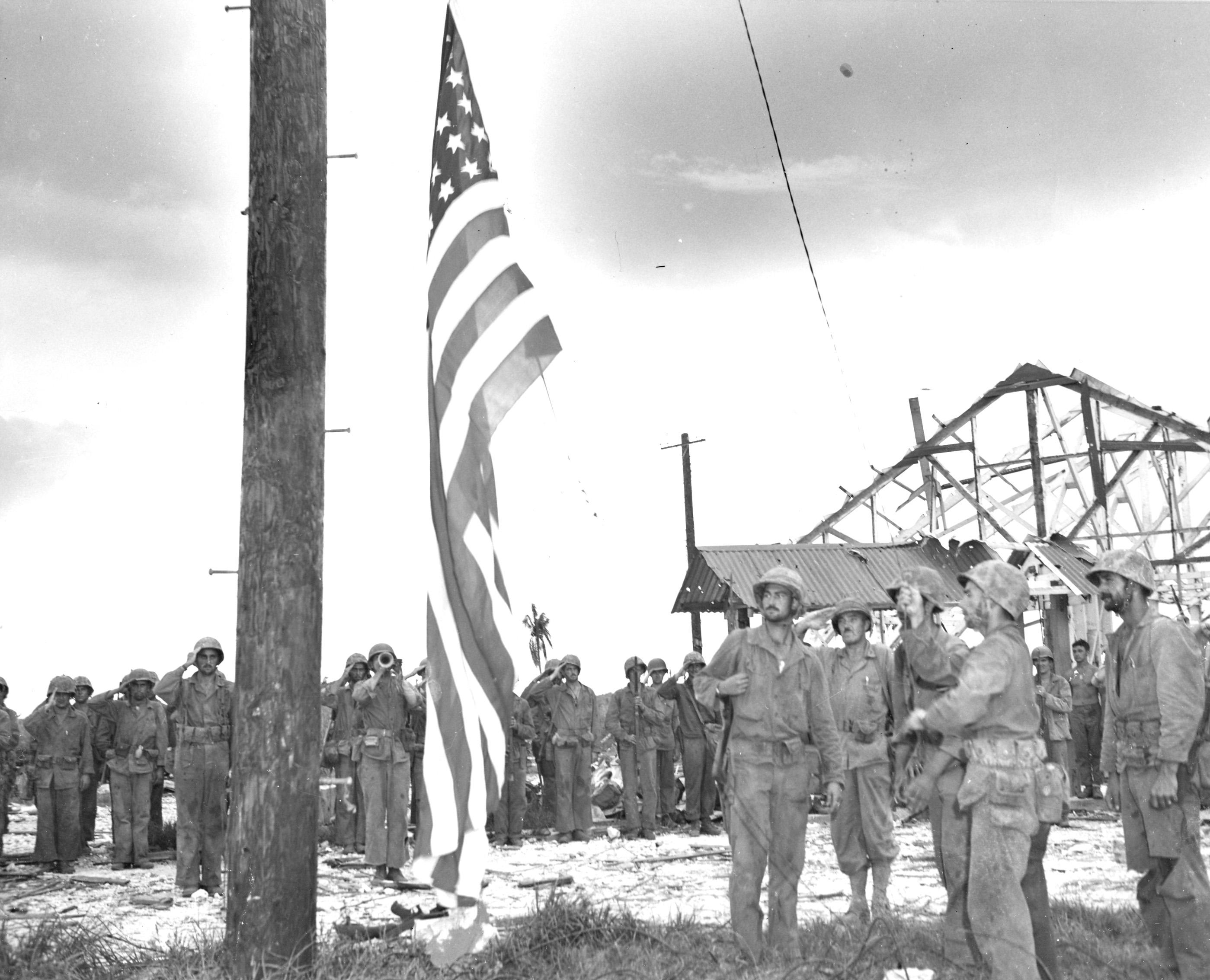 Marines raise Old Glory once again after more than two years the Marines raise the American Flag over the Marine barracks on the island of Guam.  These same Marines seen in this picture took part in the recapture of the Marine barracks just a few hours before this picture was taken.