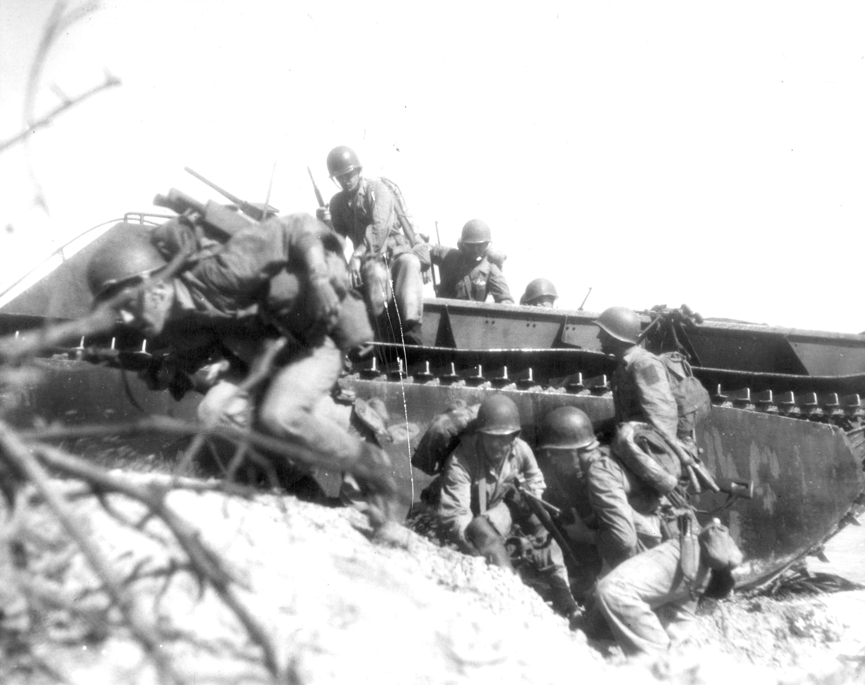 The Guam assault by the Third Marine Division and the First Marine Provisional Brigade came July 20, 1944, after a 17-day aerial and naval bombardment which established a record tonnage of explosives dropped on a Japanese position.  Opposition on the beaches, as at Saipan, was vigorous and Marines in this wave leap from their amphibious tractor for the shelter of the sand dunes.  The Marine advance was steady and the former American possession, captured by the Japanese on December 10, 1941, was completely won by August 9, 1944.