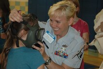 Air Force Reserve Staff Sgt. Kalee Lint, a member of the 910th Airlift Wing, helps a student try on a military issue protective mask at Lakeview Middle School May 17, 2013. Several members of the 910th volunteered to interact with students during Right to Read week. (Courtesy photo)
