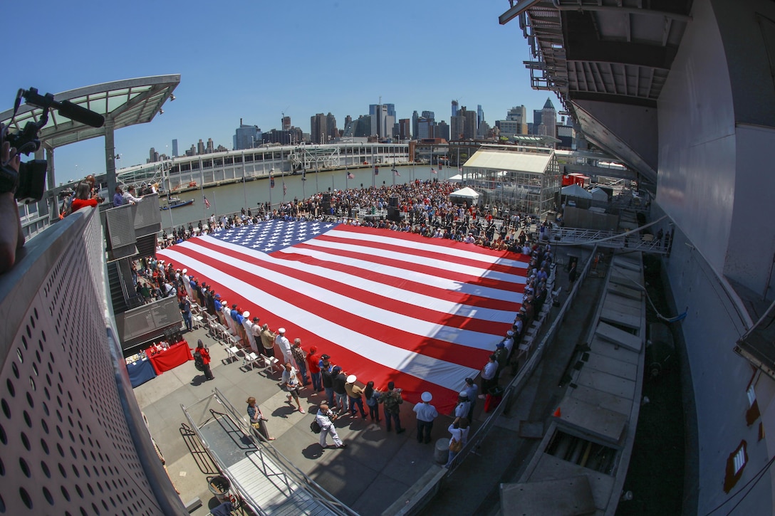 Current and veteran members of the armed forces attending the Intrepid Memorial Day Commemoration at the Intrepid Sea, Air and Space Museum in New York gather around an American flag May 27.  The various events to commemorate Memorial Day around New York are being conducted with active duty and reserve service members stationed in the Greater New York City area.  (U.S. Marine Corps photo by Sgt. Caleb Gomez).