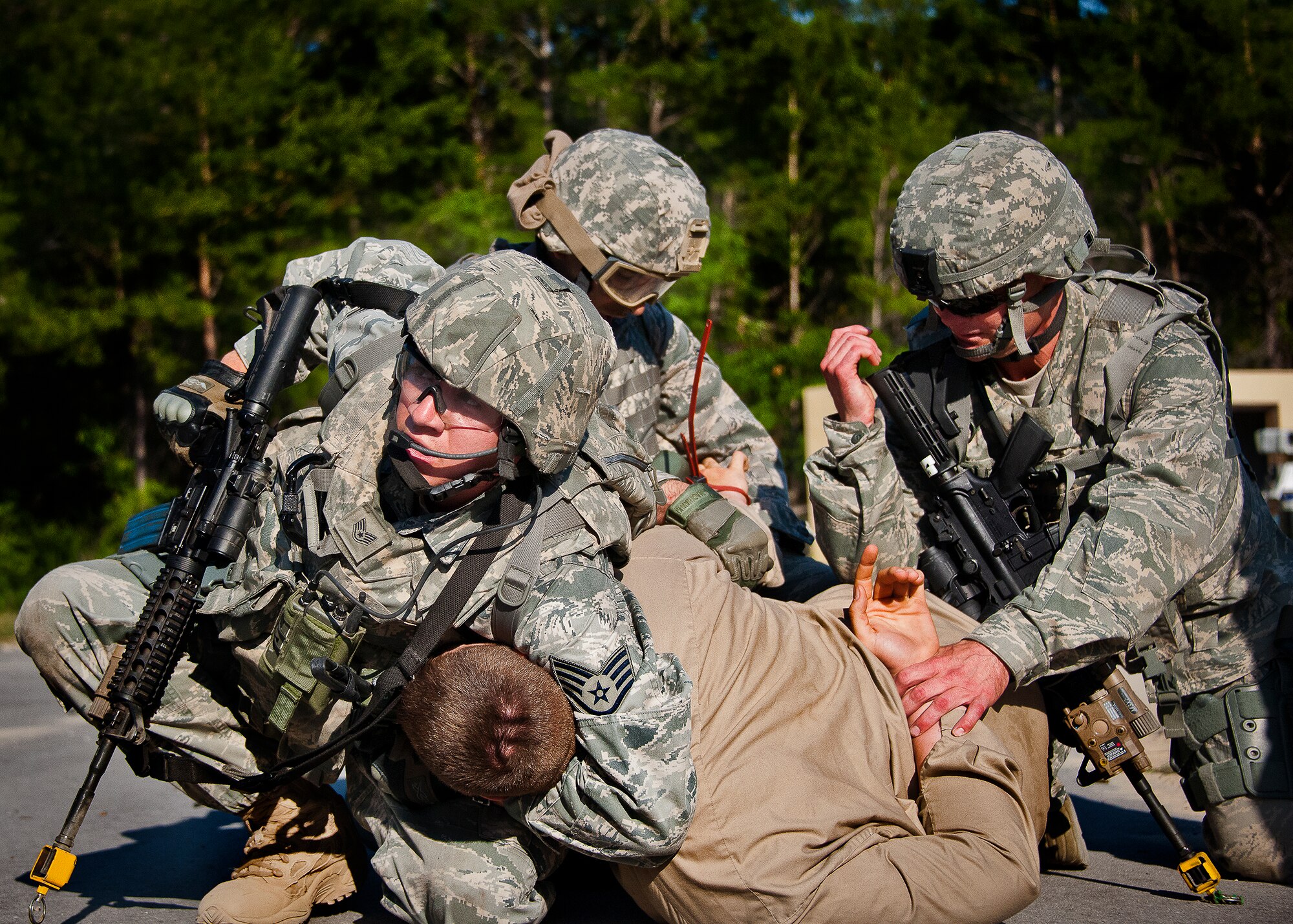 Airmen ensure a high-value-target doesn’t escape again after finding him during a village assault at the end of the three-day Brave Defender field training exercise May 20 at Eglin Air Force Base, Fla.  The exercise is the culmination of Air Force Materiel Command’s six-week security forces deployment training, administered by the 96th Ground Combat Training Squadron. GCTS instructors teach 10 training classes a year, which consists of improvised explosive device detection and reaction, operating in an urban environment, mission planning, land navigation and casualty care and more. More than 140 active-duty and National Guard Airmen attended this training. (U.S. Air Force photo/Samuel King Jr.)