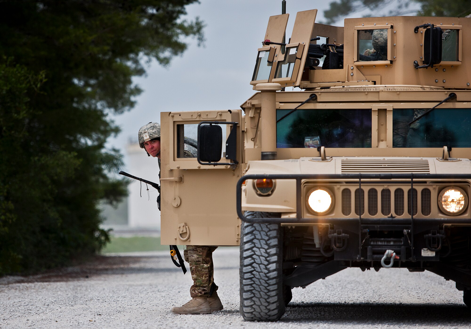 Staff Sgt. Doug Crisp, of the 94th Security Forces Squadron, peaks around the side of his HMMWV during an enemy assault on an entry control point at the three-day Brave Defender field training exercise May 19 at Eglin Air Force Base, Fla.  The exercise is the culmination of Air Force Materiel Command’s six-week security forces deployment training, administered by the 96th Ground Combat Training Squadron. GCTS instructors teach 10 training classes a year, which consists of improvised explosive device detection and reaction, operating in an urban environment, mission planning, land navigation and casualty care and more. More than 140 active-duty and National Guard Airmen attended this training. (U.S. Air Force photo/Samuel King Jr.)