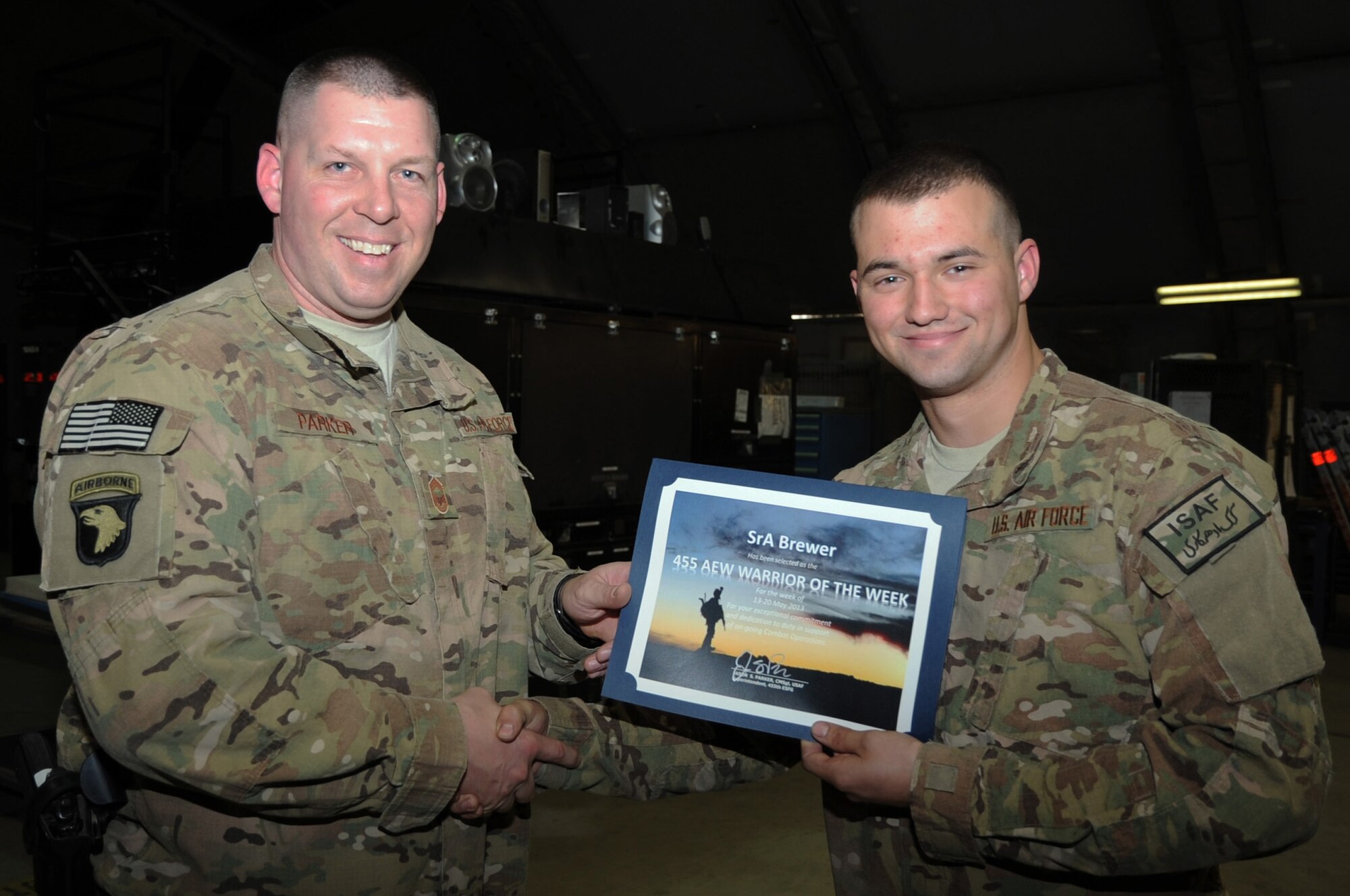 Chief Master Sgt. Jason Parker, 455th Expeditionary Security Forces Group superintendent, presents the "Warrior of the Week" award to Senior Airman Dustin Brewer, 455th Expeditionary Maintenance Squadron Inspection Section journeyman, on Bagram Airfield, Afghanistan, May 22, 2013. Brewer identified damage on aircraft parts that averted a potential in-flight emergency and achieved a 100 percent pass rate on quality assurance inspections. (U.S. Air Force photo/Staff Sgt. David Dobrydney)