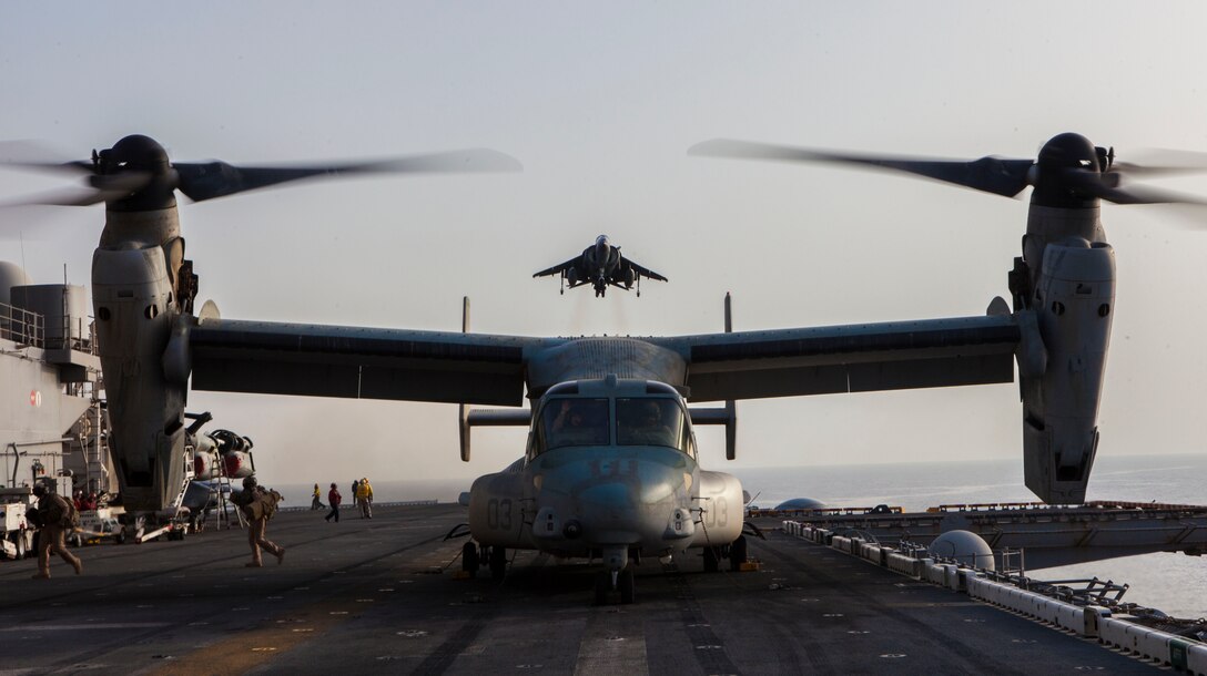 An AV-8B Harrier assigned to Marine Medium Tiltrotor Squadon (VMM) 266, (Reinforced), descends onto the flight deck of the USS Kearsarge as an MV-22B Osprey prepares to takeoff, at sea, May 27, 2013. The 26th Marine Expeditionary Unit is a Marine Air-Ground Task Force forward-deployed to the U.S. 5th Fleet area of responsibility aboard the Kearsarge Amphibious Ready Group serving as a sea-based, expeditionary crisis response force capable of conducting amphibious operations across the full range of military operations.(U.S. Marine Corps photo by Sgt. Christopher Q. Stone, 26th MEU Combat Camera/Released)
