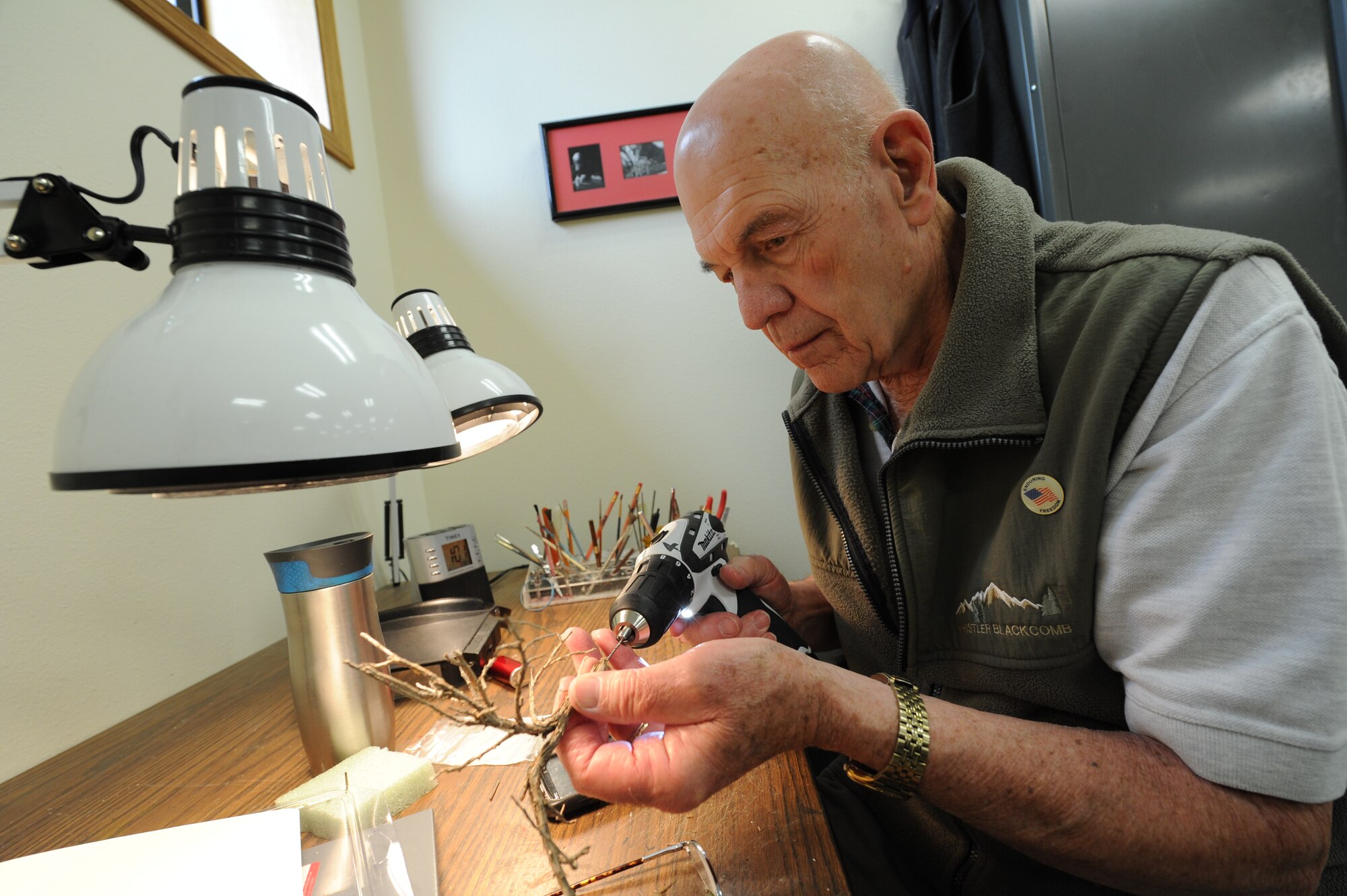 Ron Peterson, a U.S. Air Force retiree, drills a whole at the bottom of a branch for his train set he's building at Fairchild Air Force Base, Wash., May 21, 2013. Peterson served in the military for 25 years. (U.S. Air Force photo by Airman 1st Class Janelle Patiño/Released)