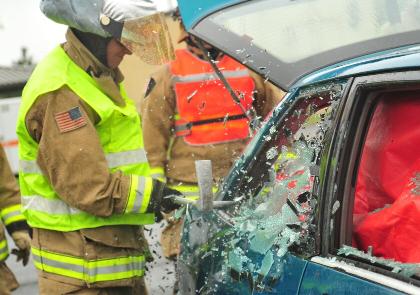 92nd Civil Engineer Squadron firefighters break the windows to a vehicle using a halligan bar to further assist a simulated victim of a car crash during a demonstration at Fairchild Air Force Base, Wash., May 22, 2013. Fairchild firefighters provide the base with firefighting protection including medical, crash and structural emergencies. (U.S. Air Force photo by Senior Airman Taylor Curry/Released)
