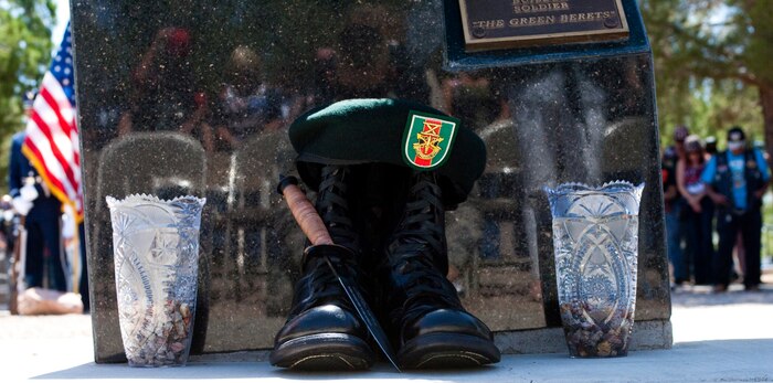A Green Beret, boots and a knife lie at the base of the Special Forces memorial while visitors bow their heads in prayer at the Southern Nevada Veterans Memorial Cemetery, May 26, 2013, in Las Vegas. During the ceremony, speakers honored the fallen and prayed for an end to war. (U.S. Air Force photo by Airman 1st Class Joshua Kleinholz)