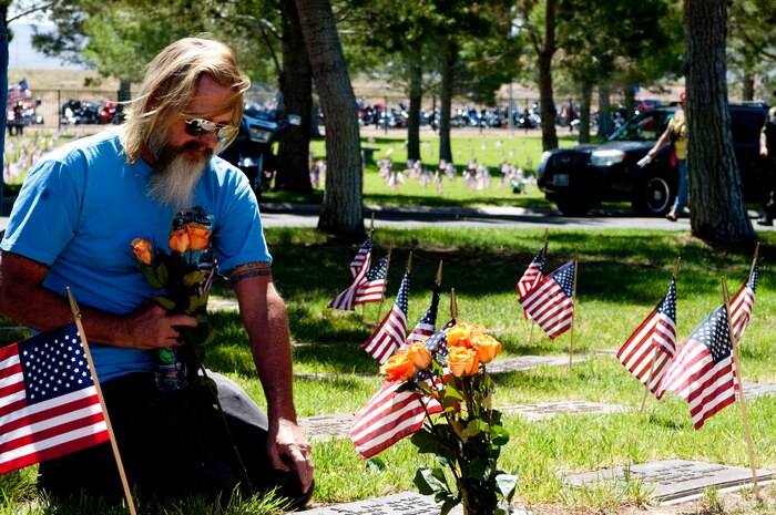 Greg McClain, an attendant of the 2013 Special Forces Memorial, kneels at the grave of his father, U.S. Air Force Lt. Col. Roland D. McClain, May 26, 2013, at the Southern Nevada Veterans Memorial Cemetery in Las Vegas. In the day prior to the event, 24,000 U.S. flags were placed at the gravesites of veterans from all branches of the military. (U.S. Air Force photo by Airman 1st Class Joshua Kleinholz)