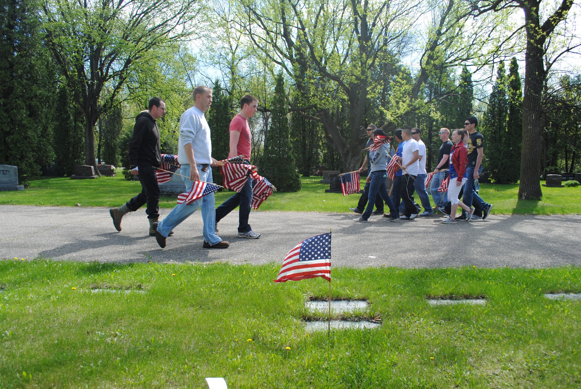 Volunteers from Grand Forks Air Force Base, N.D., cross paths as they continue to look for more U.S. veteran gravesites at Calvary Cemetery in Grand Forks, N.D., May 24, 2013. More than 100 volunteers observed this year’s Memorial Day by placing small American flags over 32 acres of cemetery plots that serve as the final resting place for more than 1,000 U.S. service members. (U.S. Air Force photo/Staff Sgt. Luis Loza Gutierrez)
