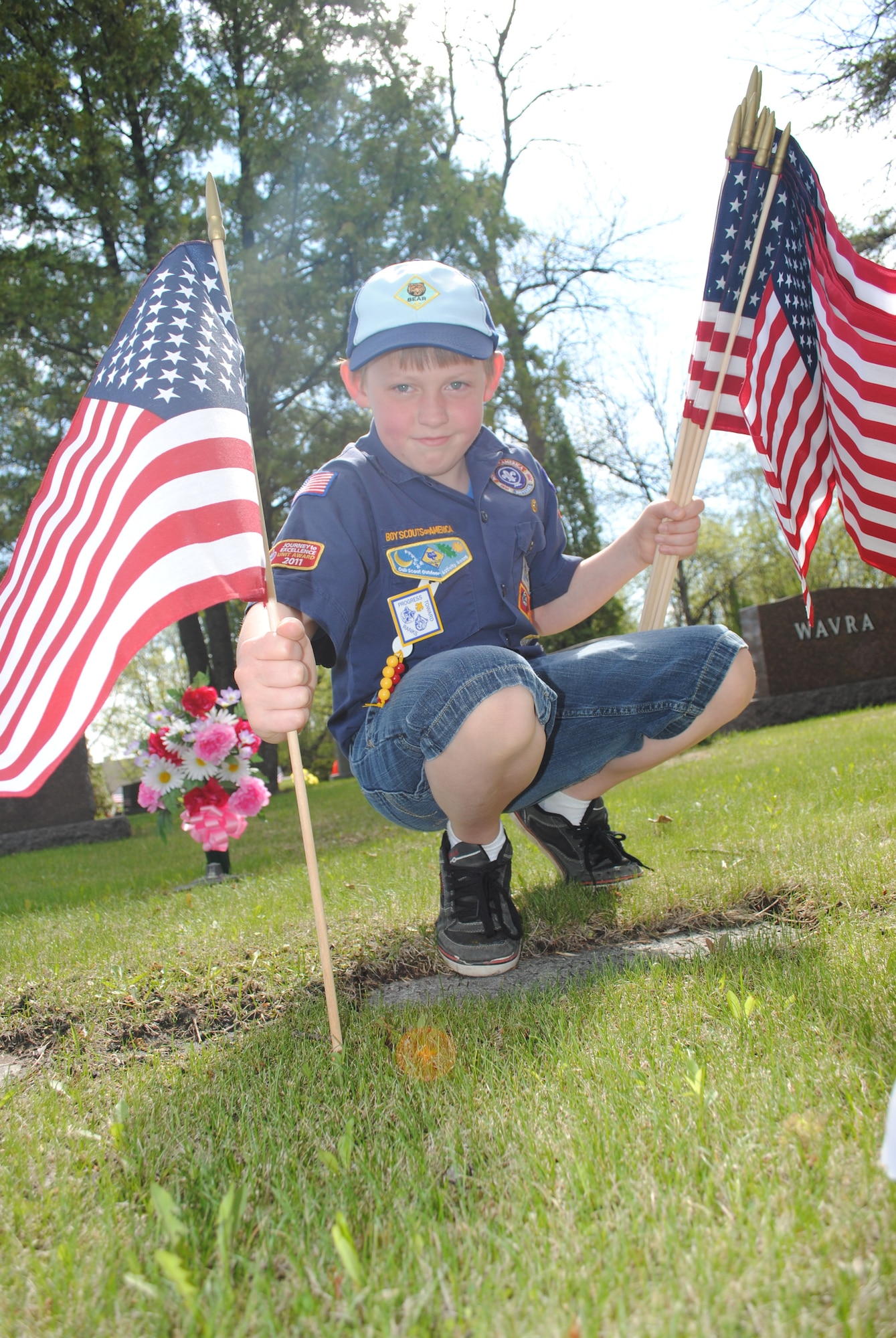 Tyler Herman, a Cub Scout with Troop 319, looks for a good spot to place a U.S. flag on the gravesite of a soldier who served in the Spanish-American War during a volunteer effort on May 24, 2013, at Calvary Cemetery in Grand Forks, N.D., in honor of Memorial Day. Herman was one of about a dozen military children from Grand Forks Air Force Base, N.D., who helped place U.S. flags on hundreds of gravesites. (U.S. Air Force photo/Staff Sgt. Luis Loza Gutierrez)
