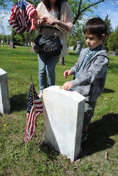 Three-year old Zachariah David places a small wild flower on top of a veteran’s tomb May 24, 2013, at Calvary Cemetery in Grand Forks, N.D., in honor of Memorial Day. More than 100 Airmen and family members from Grand Forks Air Force Base, N.D., volunteered to place flags on the tombs of deceased U.S. service members in honor of Memorial Day. (U.S. Air Force photo/Staff Sgt. Luis Loza Gutierrez)