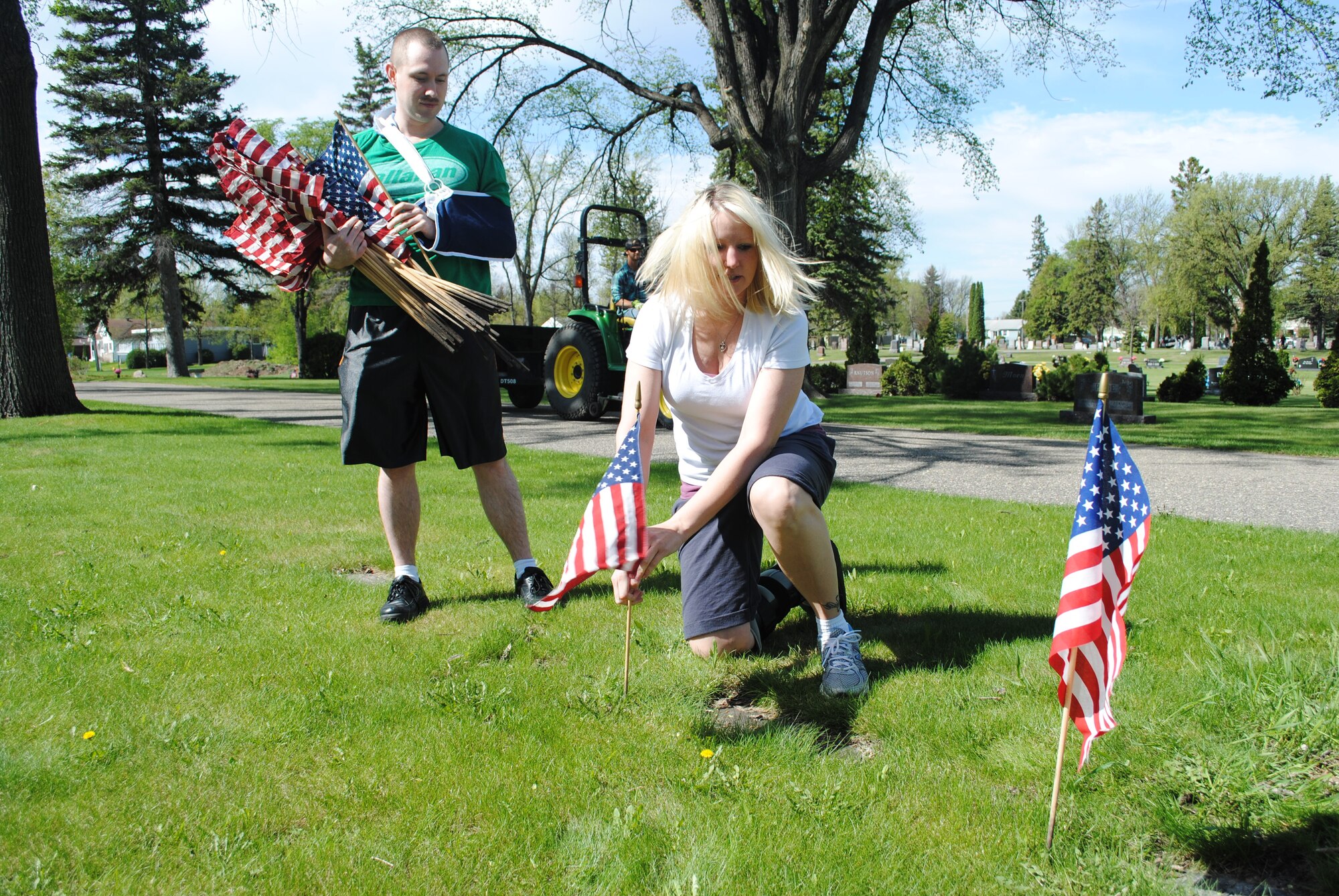 Tech. Sgt. Jamie Cleveland places a U.S. flag next to a veteran’s tomb while Airman 1st Class James Miles assists during a volunteer effort at Calvary Cemetery in Grand Forks, N.D., on May 24, 2013. They were part of a group of more than 100 Airmen and family members from Grand Forks Air Force Base, N.D., who volunteered in honor of Memorial Day.  (U.S. Air Force photo/Staff Sgt. Luis Loza Gutierrez)