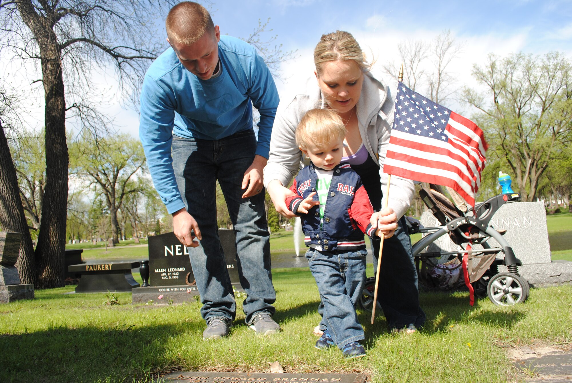 Senior Airman James Russell and his wife, Jessica, help their 18-month-old son, Elijah, place a small U.S. flag at Calvary Cemetery in Grand Forks, N.D., on May 24, 2013. The Russells were part of a group of about 100 Airmen and family members from Grand Forks Air Force Base, N.D., who volunteered to place flags on the tombs of deceased U.S. service members in honor of Memorial Day.(U.S. Air Force photo/Staff Sgt. Luis Loza Gutierrez)