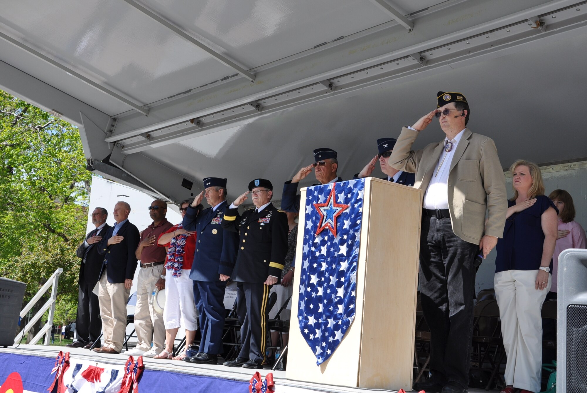 Distinguished guests of the 2013 Memorial Day Parade salute or hold their hands over their hearts as a U.S. flag passes the parade review stand May 25, 2013 in Denver. Spectators saluted, applauded and waved at the approximately 40 parade entries. (U.S. Air Force photo by Staff Sgt. Kali L. Gradishar/Released)