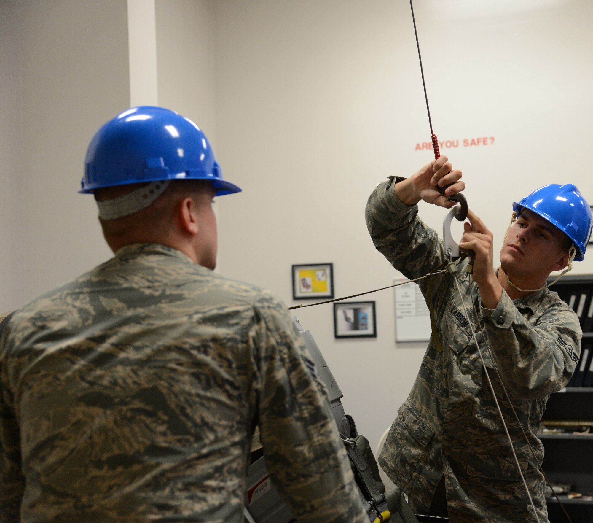 U.S. Air Force Senior Airman Kenneth Hay (Left) and Airman 1st Class Tyler Larson attach a cable to a beam in an egress classroom, May 22, 2013 at Detachment 202, 372nd Training Squadron, Shaw Air Force Base, S.C. Egress students learned all about the cockpit of an F-16 Fighting Falcon. (U.S. Air Force photo by Airman 1st Class Jonathan Bass/Released)