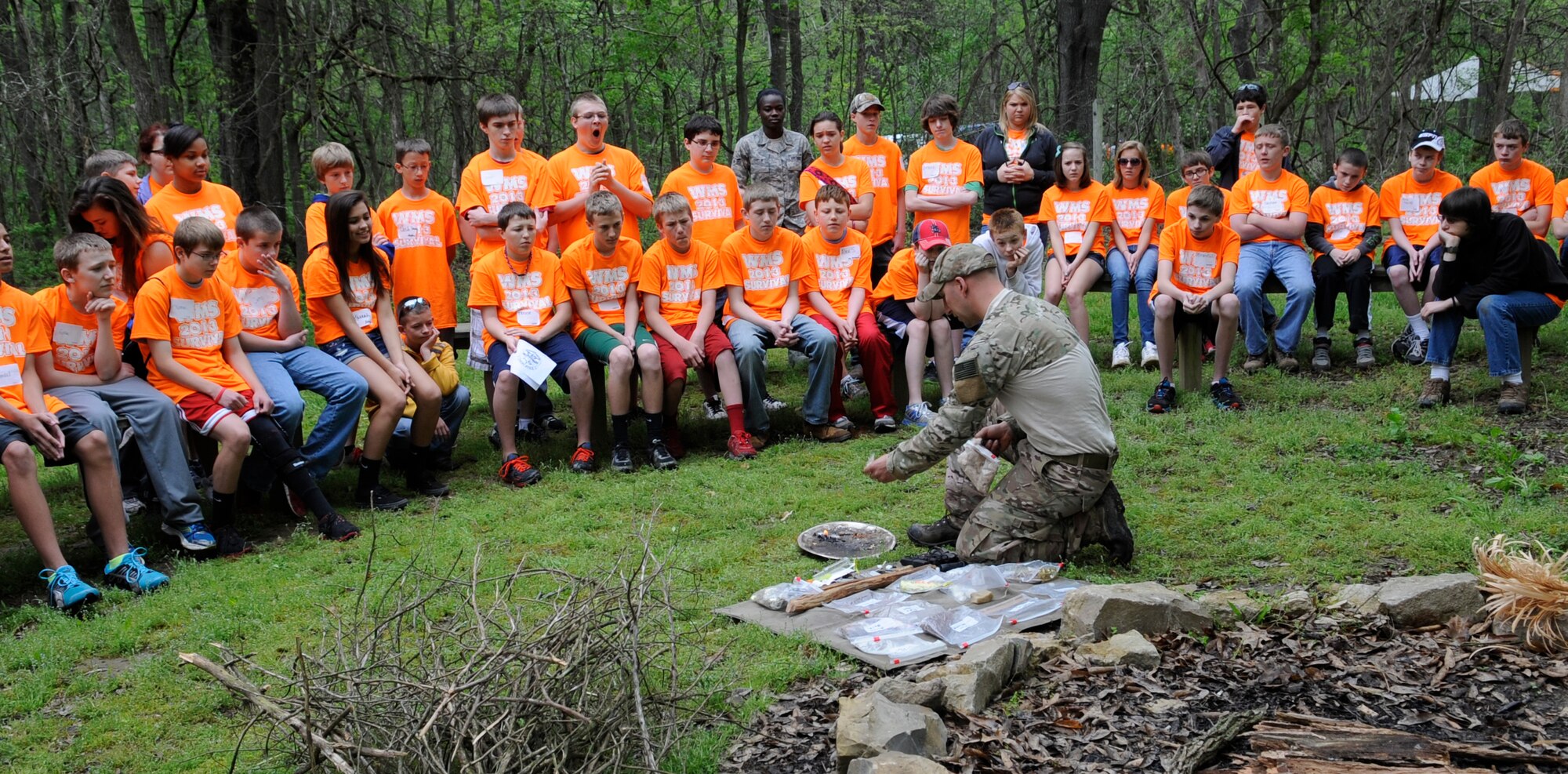 Warrensburg Middle School seventh graders watch as Tech. Sgt. Matthew Garcia, 509th Operations Support Squadron survival, evasion, resistance and escape (SERE) specialist, builds a fire during the students’ field day in Knob Noster State Park, Mo., May 10, 2013. The students participated in a survival scenario quiz before they were separated in two groups for survival skills familiarization. (U.S. Air Force photo by Staff Sgt. Alexandra M. Boutte/Released)