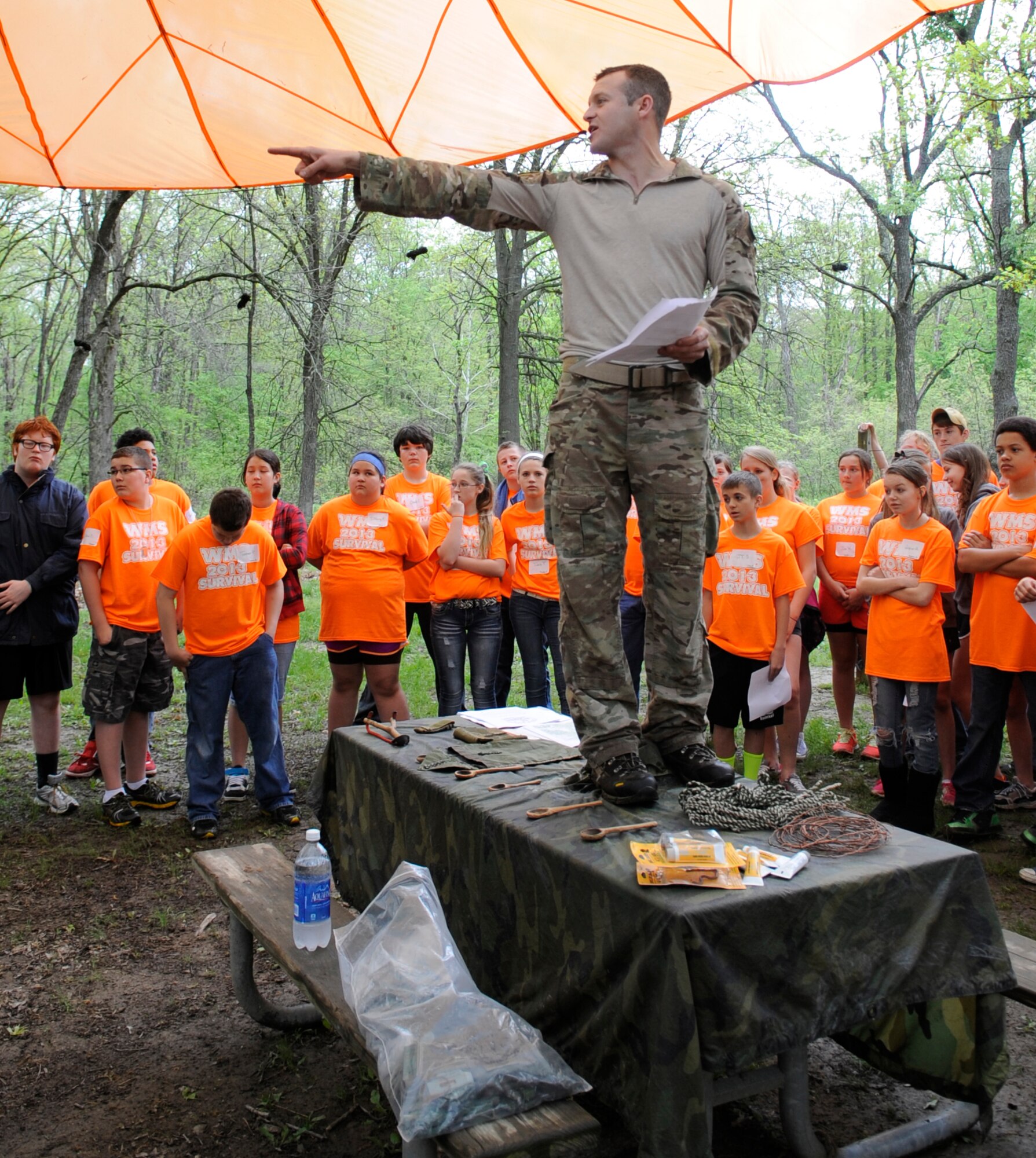 Staff Sgt. Cliff Cleveland, 509th Operations Support Squadron survival, evasion, resistance and escape (SERE) specialist, explains a survival scenario to Warrensburg Middle School seventh-graders in Knob Noster State Park, Mo., May 10, 2013. More than 140 students learned about several different types of shelters and how to build a fire during their field day. (U.S. Air Force photo by Staff Sgt. Alexandra M. Boutte/Released)