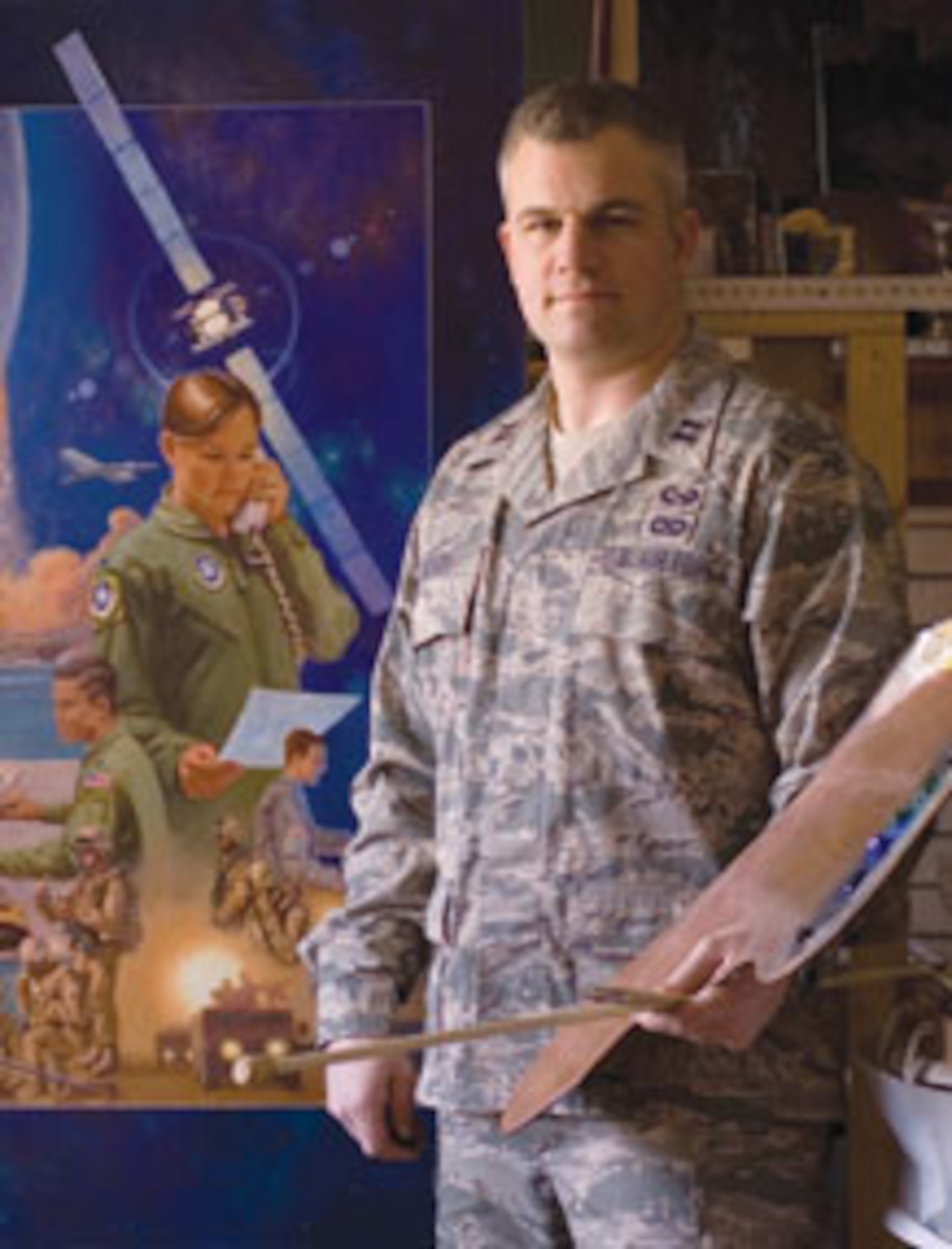 Air Force Reservist and artist Maj. Warren Neary, pictured here as a captain, with the completed painting entitled “AFSPC Wideband Global SATCOM System Support to Warfighter Operations,” also included in the Air Force Art Collection. Major Neary has completed twenty paintings for the Air Force Art Program. He has been painting for more than 20 years. (Courtesy Photo)