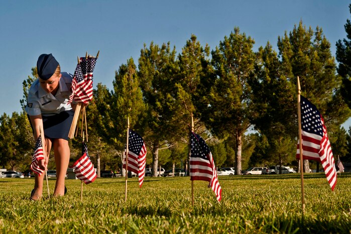 U.S. Air Force Senior Airman Kaila Kelly, 57th Weapons School aviation resource manager, places flags in the ground over veterans’ memorial plots May 25, 2013, at the Southern Nevada Veterans Memorial Cemetery, Boulder City, Nev. More than 24,000 flags were placed on cemetery plots of veterans of the U.S. armed forces. (U.S. Air Force photo by Senior Airman Daniel Hughes)