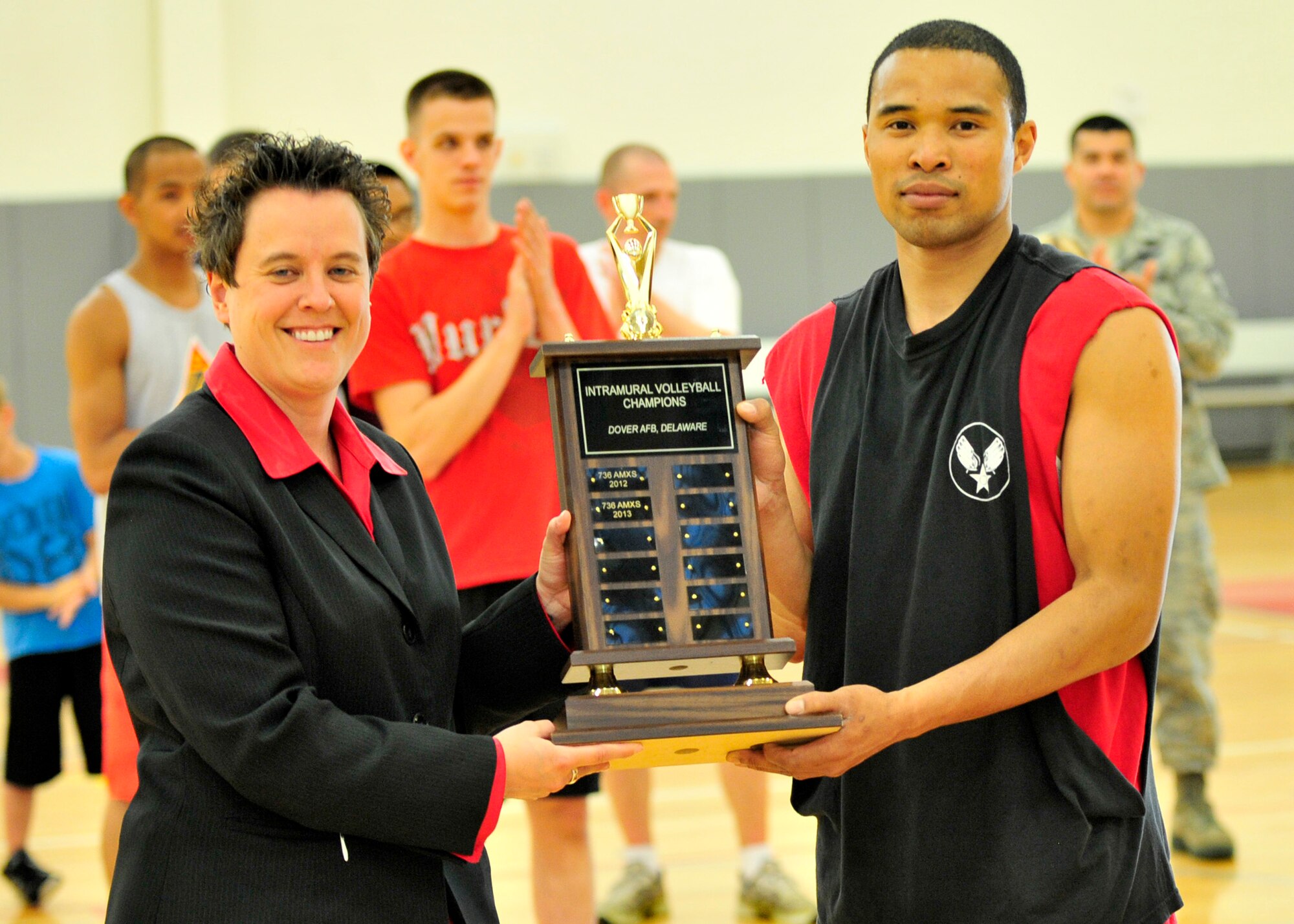 James Jones, 736th Aircraft Maintenance Squadron player-coach, receives the intramural volleyball championship trophy from Holly Mehringer, 436th Mission Support Group deputy commander, May 21, 2013, at the fitness center on Dover Air Force Base, Del. The 736th AMXS won the title for the third year in a row defeating the 436th Maintenance Squadron 25-19, 14-25, and 17-15. (U.S. Air Force photo/Tech. Sgt. Chuck Walker)
