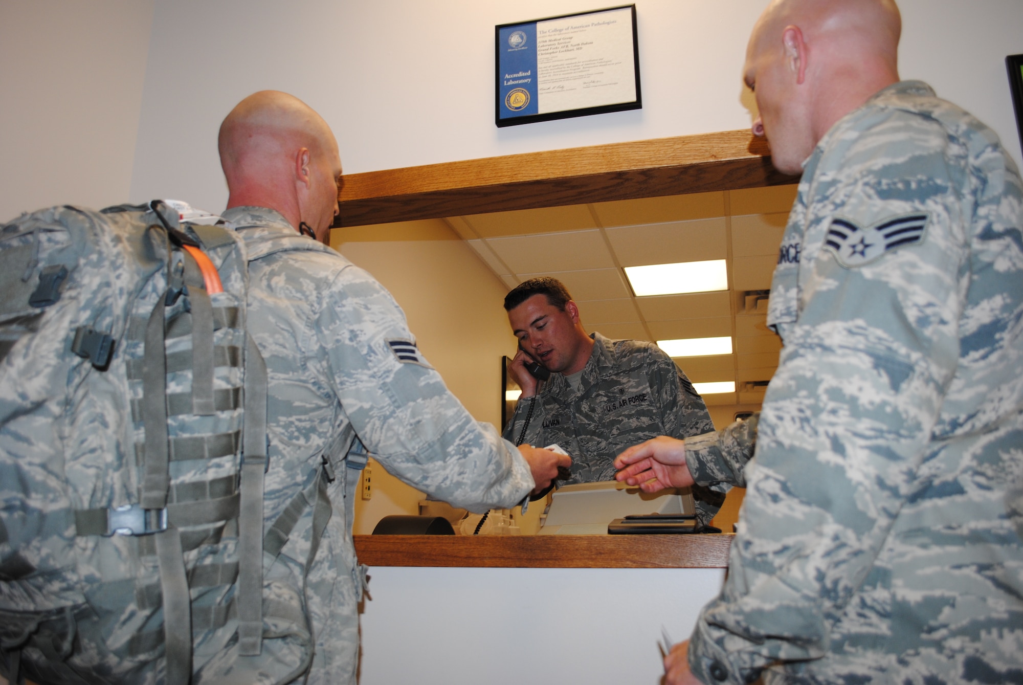 Staff Sgt. Thomas C. Sullivan Jr., 319th Medical Support Squadron laboratory technician, helps members of the 319th Security Forces Squadron in-process May 22, 2013, at the medical laboratory on Grand Forks Air Force Base, N.D. Lab patients must provide proper identification, such as a military ID before providing a medical sample. (U.S. Air Force photo/Staff Sgt. Luis Loza Gutierrez)
