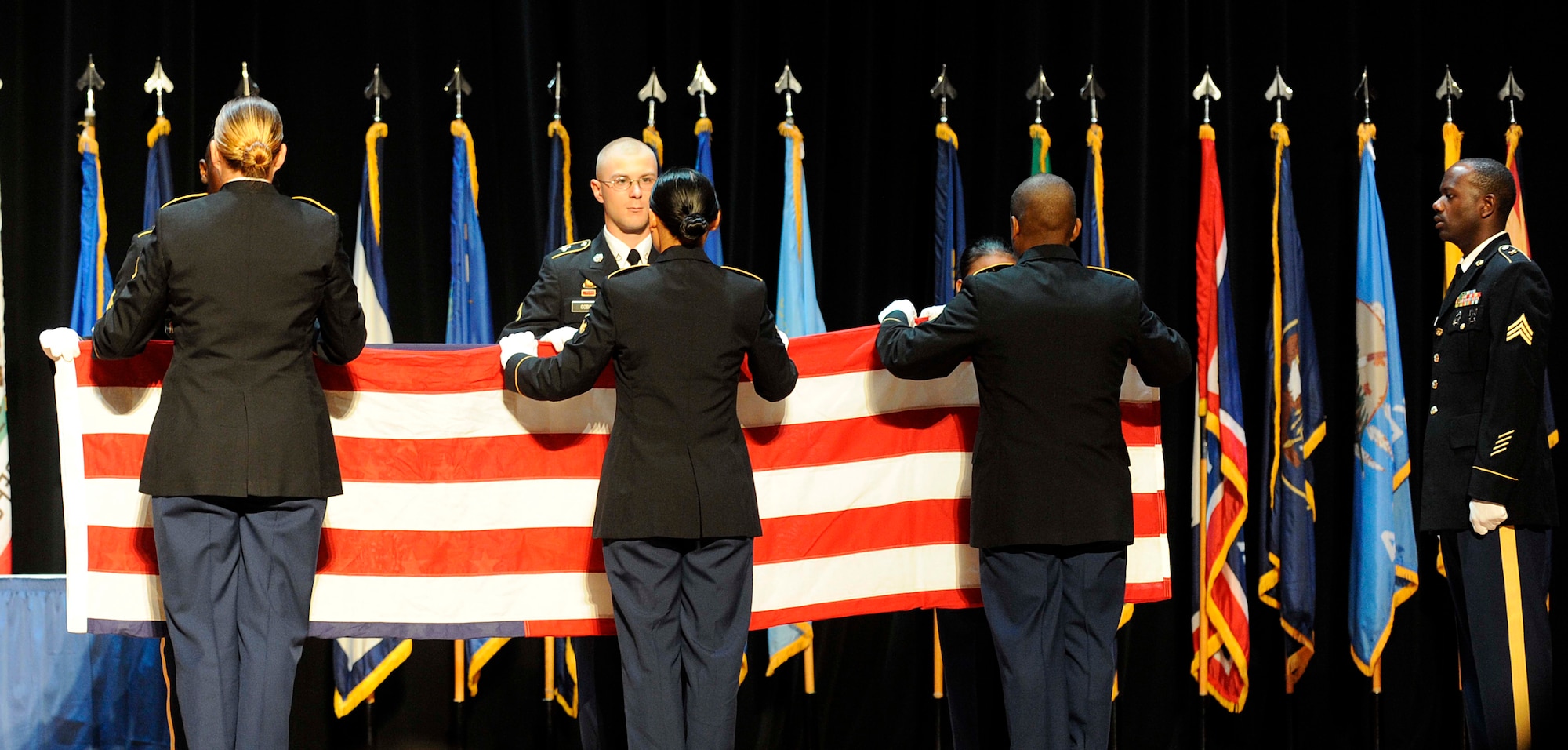 Soldiers from the 7th Sustainment Brigade perform a flag folding ceremony during the Memorial Day Ceremony at Jacobs Theater at Fort Eustis, Va., May 23, 2013. The ceremony included a guest speaker, a performance by the U.S. Army Training and Doctrine Command Band and a 21-gun salute in honor of fallen U.S. Service members. (U.S. Air Force photo by Staff Sgt. Dana Hill/Released)