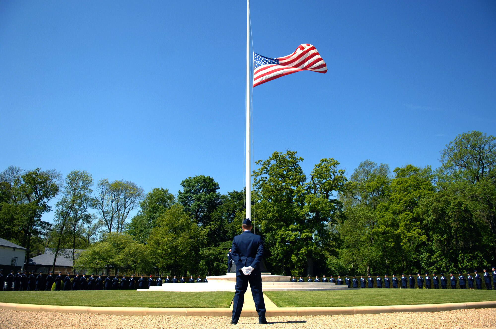 An Airman stands at parade rest in front of an American flag at half-staff during a Memorial Day ceremony May 27, 2013, at the Madingley American Cemetery in Cambridge, England. Memorial Day is an annual tradition honoring fallen service members. (U.S. Air Force photo by Airman 1st Class Dillon Johnston/Released)