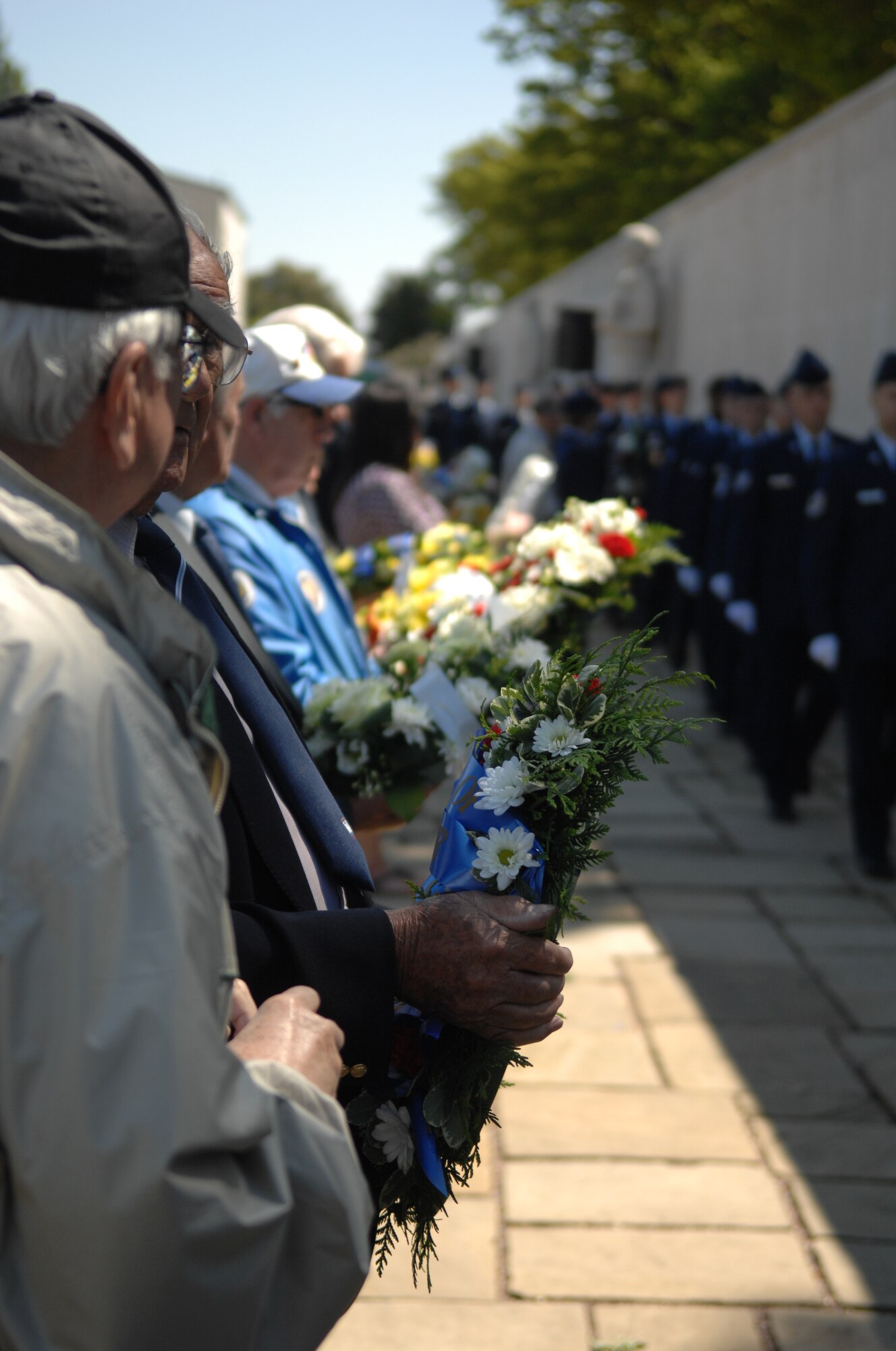 Veterans and their families hold wreaths as Airmen march past them during a Memorial Day ceremony May 27, 2013, at the Madingley American Cemetery in Cambridge, England. The wreaths are given in remembrance of service members who died during World War II. (U.S. Air Force photo by Airman 1st Class Dillon Johnston/Released)