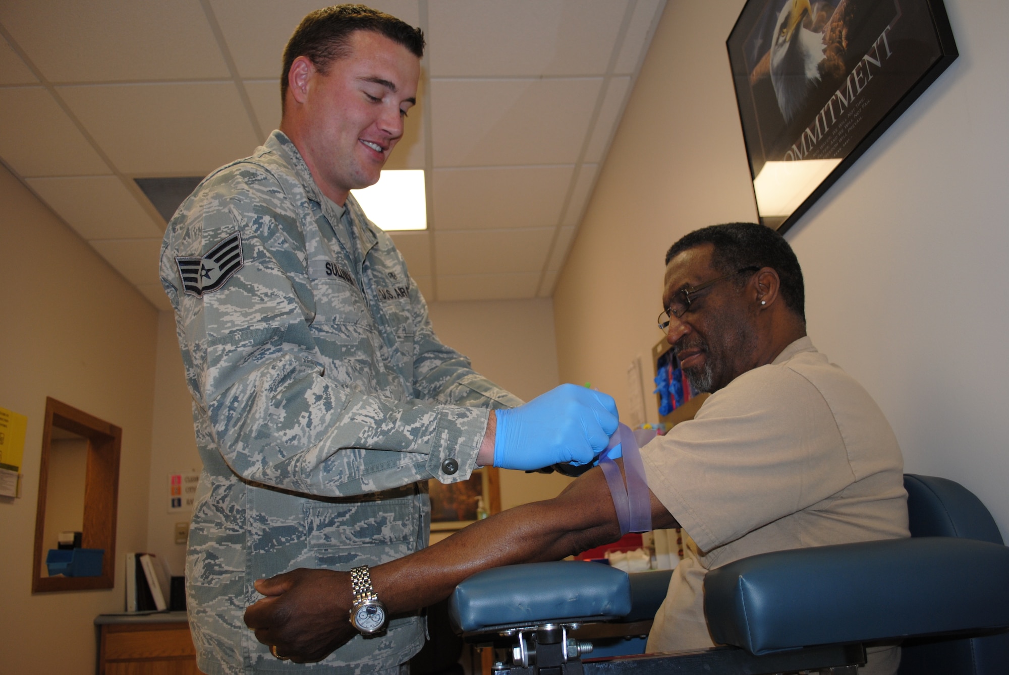 Staff Sgt. Thomas C. Sullivan Jr., 319th Medical Support Squadron laboratory technician, wraps the left arm of retired Master Sgt. Stephen Tyler with a rubber band prior to taking a blood sample May 22, 2013, at the medical laboratory on Grand Forks Air Force Base, N.D. Rubber bands restrict blood flow in the arm, which cause veins to dilate allowing lab techs to select the most suitable vein to draw a blood sample from. (U.S. Air Force photo/Staff Sgt. Luis Loza Gutierrez)

