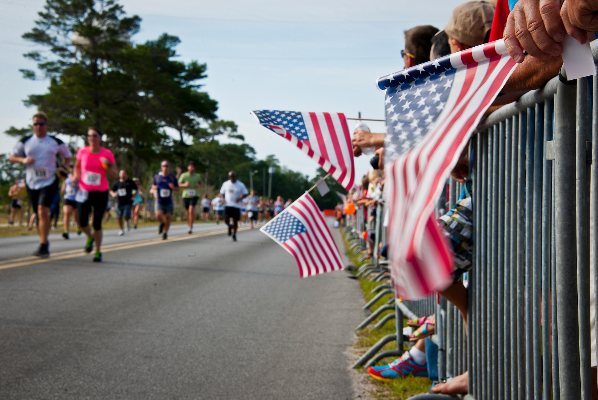 Flags were waved as the runners sprinted to the finish line at the 28th annual Gate-to-Gate Run May 27 at Eglin Air Force Base, Fla. More than 1,500 people participated in the Memorial Day race.  Many of the runners paid their respects by dropping off flowers in front of the All Wars Memorial as they raced by.  (U.S. Air Force photo/Samuel King Jr.)