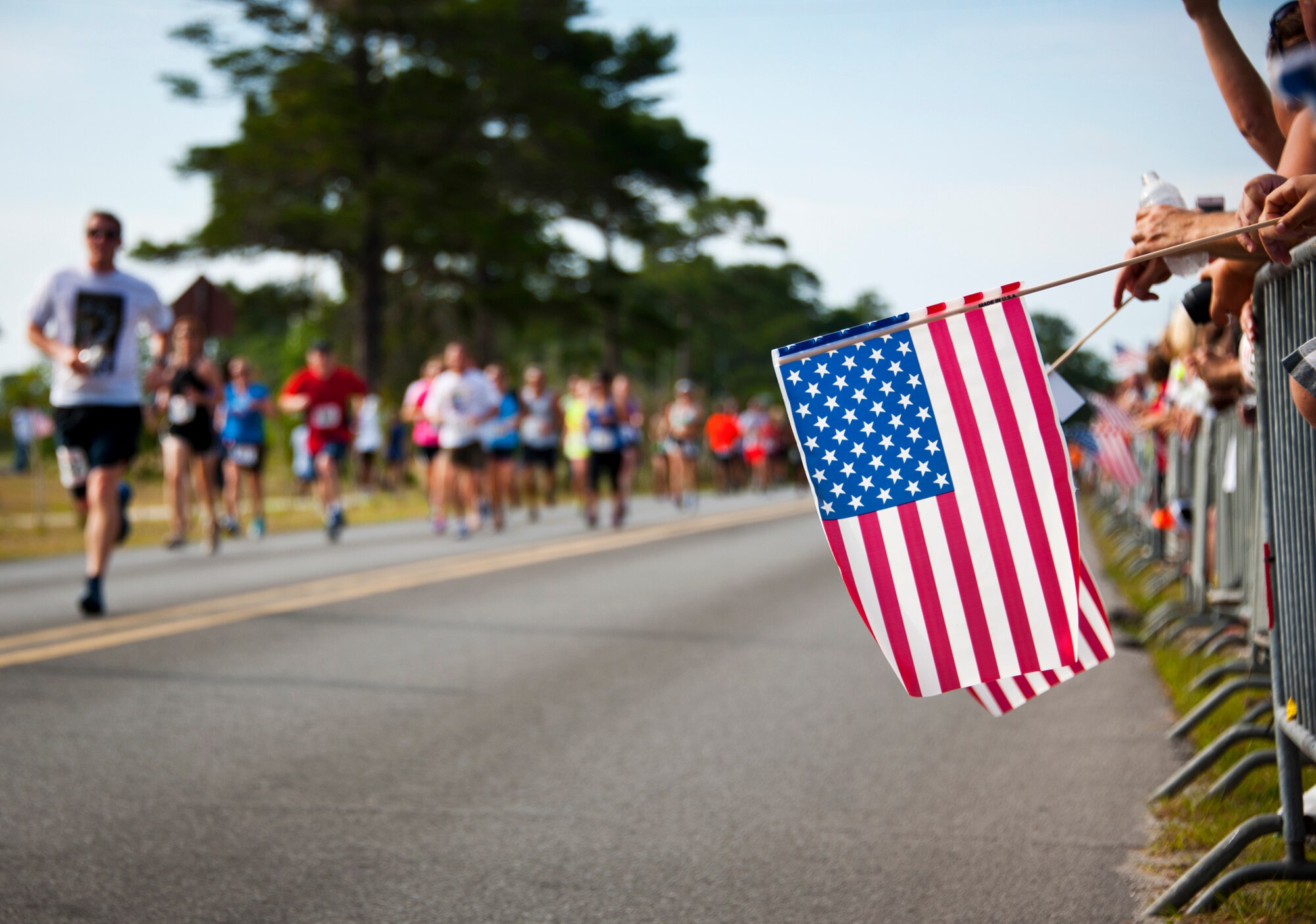 Flags were waved as the runners sprinted to the finish line at the 28th annual Gate-to-Gate Run May 27 at Eglin Air Force Base, Fla. More than 1,500 people participated in the Memorial Day race.  Many of the runners paid their respects by dropping off flowers in front of the All Wars Memorial as they raced by.  (U.S. Air Force photo/Samuel King Jr.)