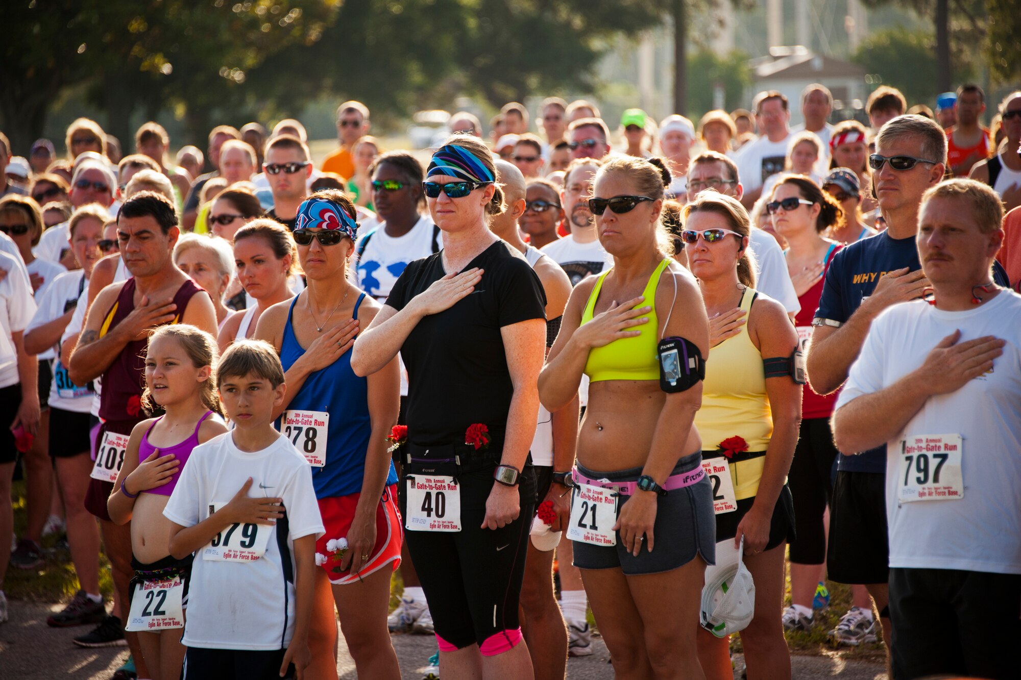 Everyone in the crowd held their hand to their heart or stood at attention during the National Anthem at the 28th annual Gate to Gate Run May 27 at Eglin Air Force Base, Fla.  More than 1,500 people participated in the Memorial Day race.  Many of the runners paid their respects by dropping off flowers in front of the All Wars Memorial as they raced by.  (U.S. Air Force photo/Samuel King Jr.)