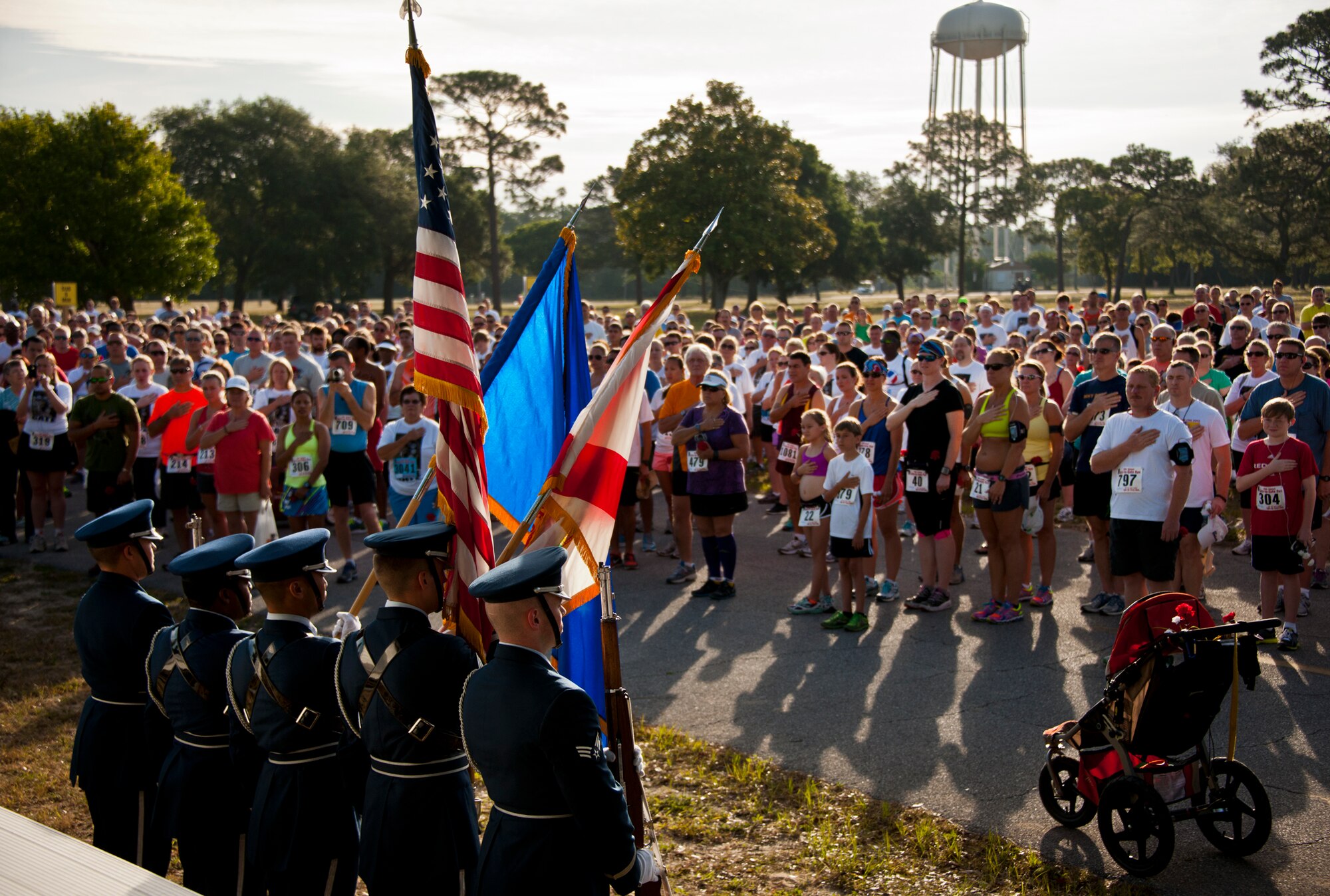 Everyone in the crowd held their hand to their heart or stood at attention during the National Anthem at the 28th annual Gate to Gate Run May 27 at Eglin Air Force Base, Fla.  More than 1,500 people participated in the Memorial Day race.  Many of the runners paid their respects by dropping off flowers in front of the All Wars Memorial as they raced by.  (U.S. Air Force photo/Samuel King Jr.)