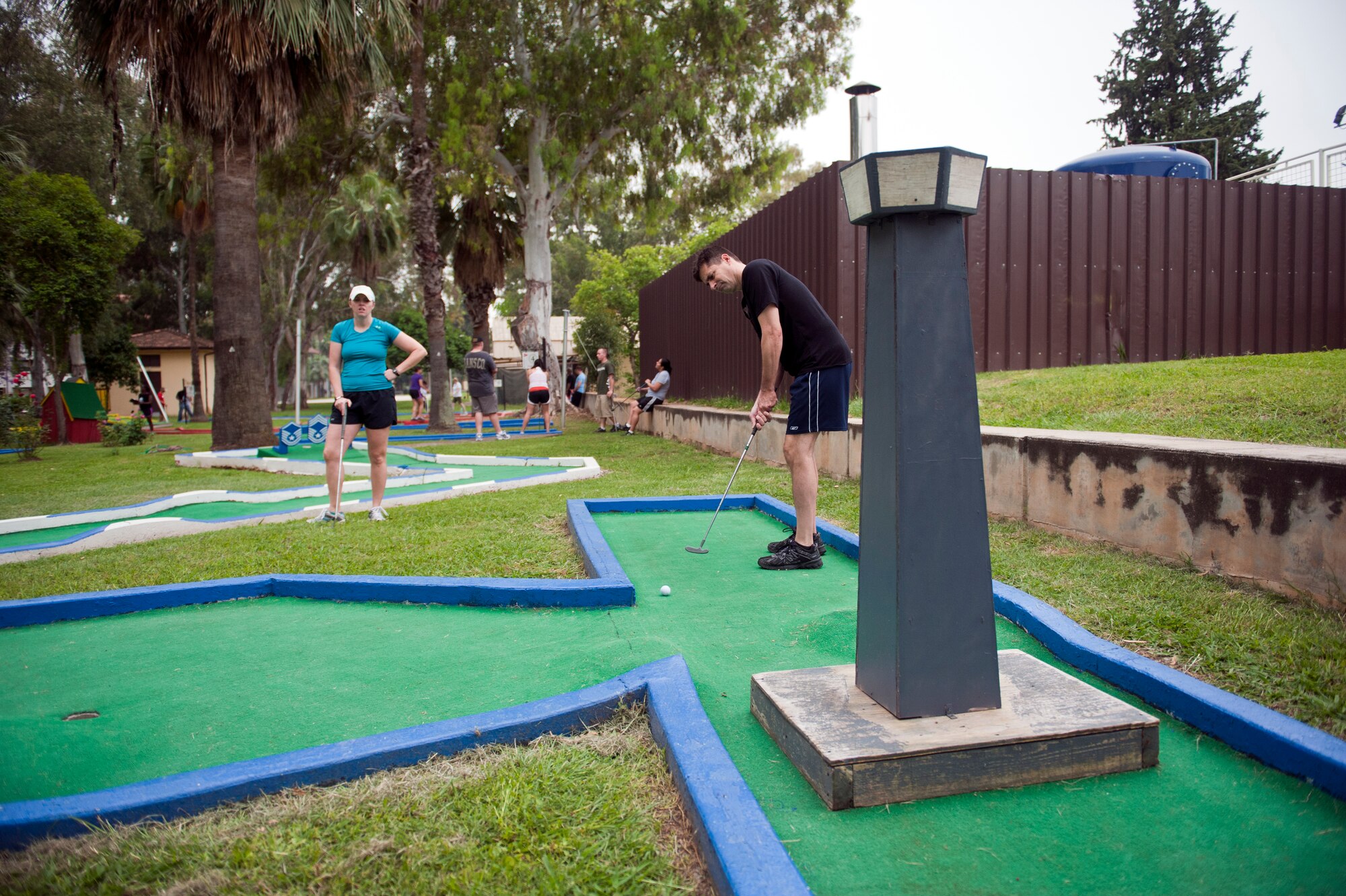 Marty Fields, 39th Air Base Wing, takes a stroke on the putt-putt golf course while Mindy Dahl, 39th Comptroller Squadron, observes May 24, 2013, at Incirlik Air Base, Turkey. The putt-putt tournament was part of 39th ABW Sports Day, which included events such as kickball, volleyball and a 5K race. (U.S. Air Force photo by Senior Airman Daniel Phelps/Released)