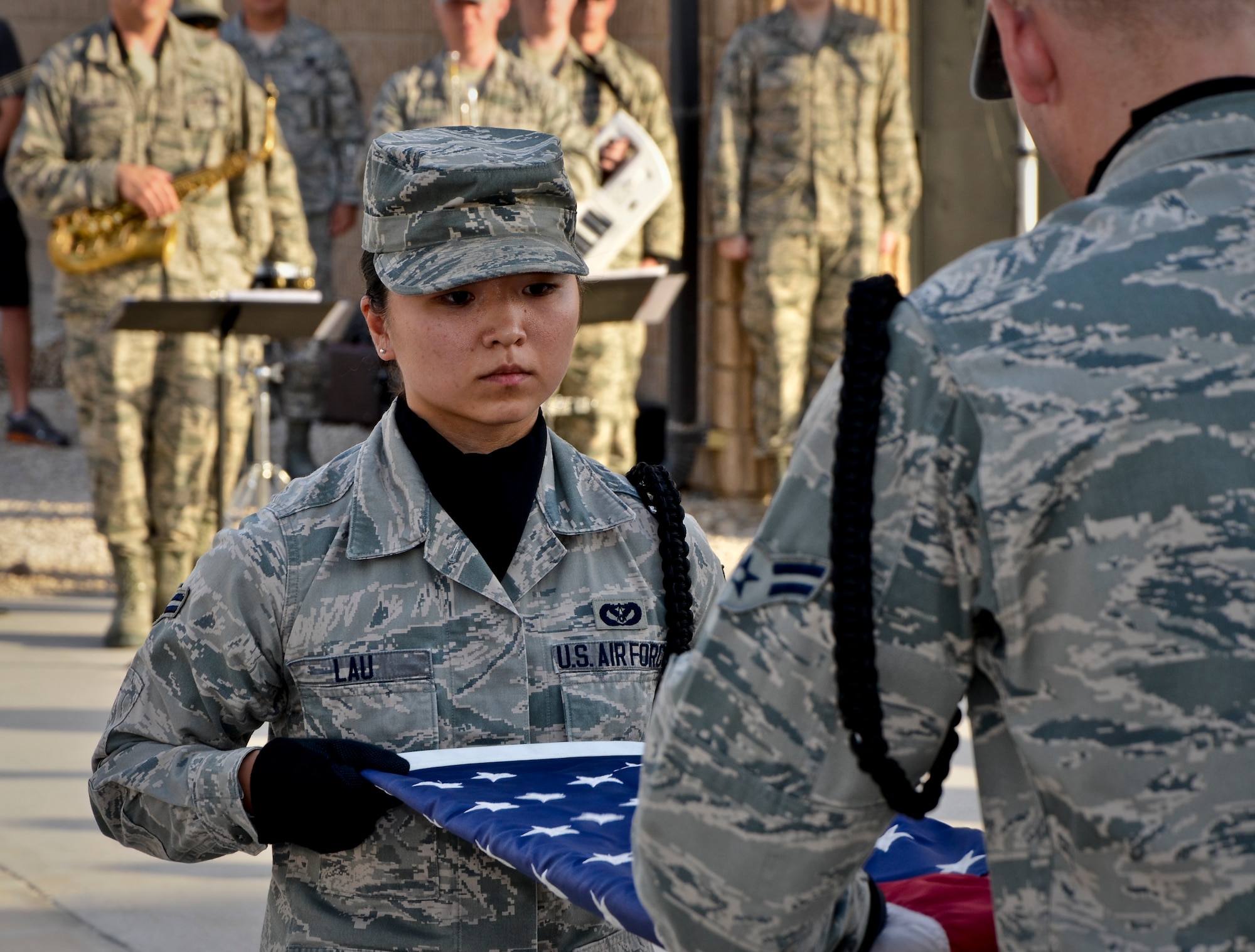 Airmen 1st Class Lena Lau and Justin Grahn fold the American flag during a Memorial Day retreat ceremony, May 27, 2013, at Memorial Plaza in Southwest Asia. Lau and Grahn are members of the 379th Air Expeditionary Wing honor guard. Military retreat ceremonies serve a twofold purpose: to signal the end of the official duty day and to pay respect to the U.S. flag. (U.S. Air Force photo/Senior Airman Benjamin Stratton)