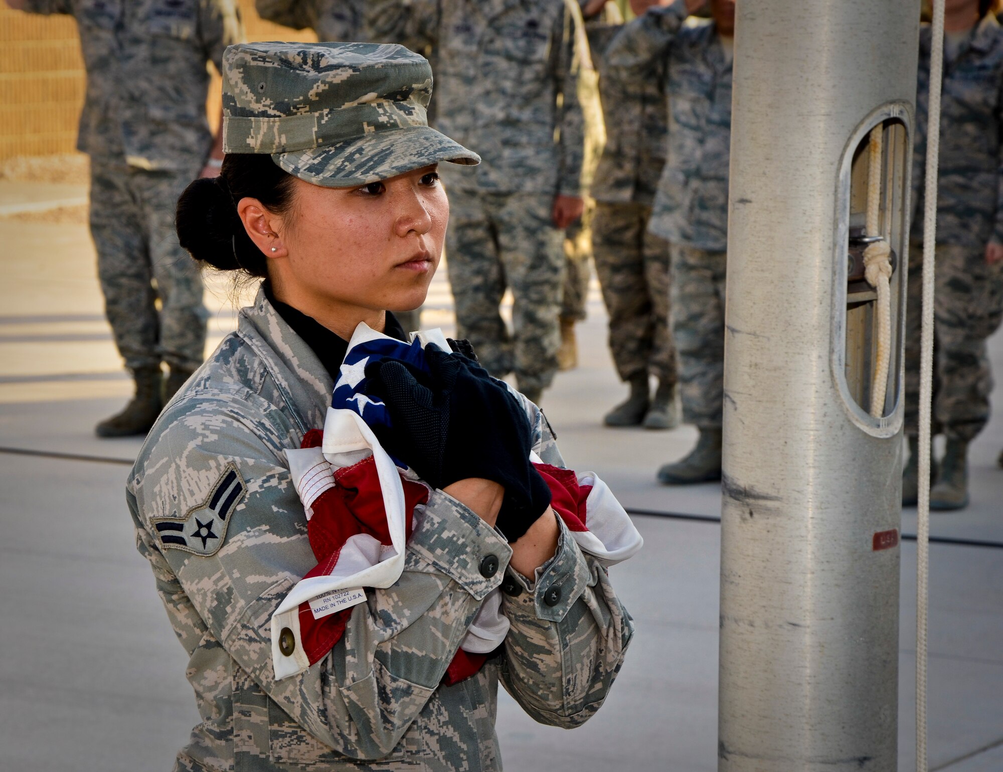 Airman 1st Class Lena Lau secures the American flag during a Memorial Day retreat ceremony, May 27, 2013, at Memorial Plaza in Southwest Asia. Lau is a member of the 379th Air Expeditionary Wing honor guard. Military retreat ceremonies serve a twofold purpose: to signal the end of the official duty day and to pay respect to the U.S. flag. (U.S. Air Force photo/Senior Airman Benjamin Stratton)