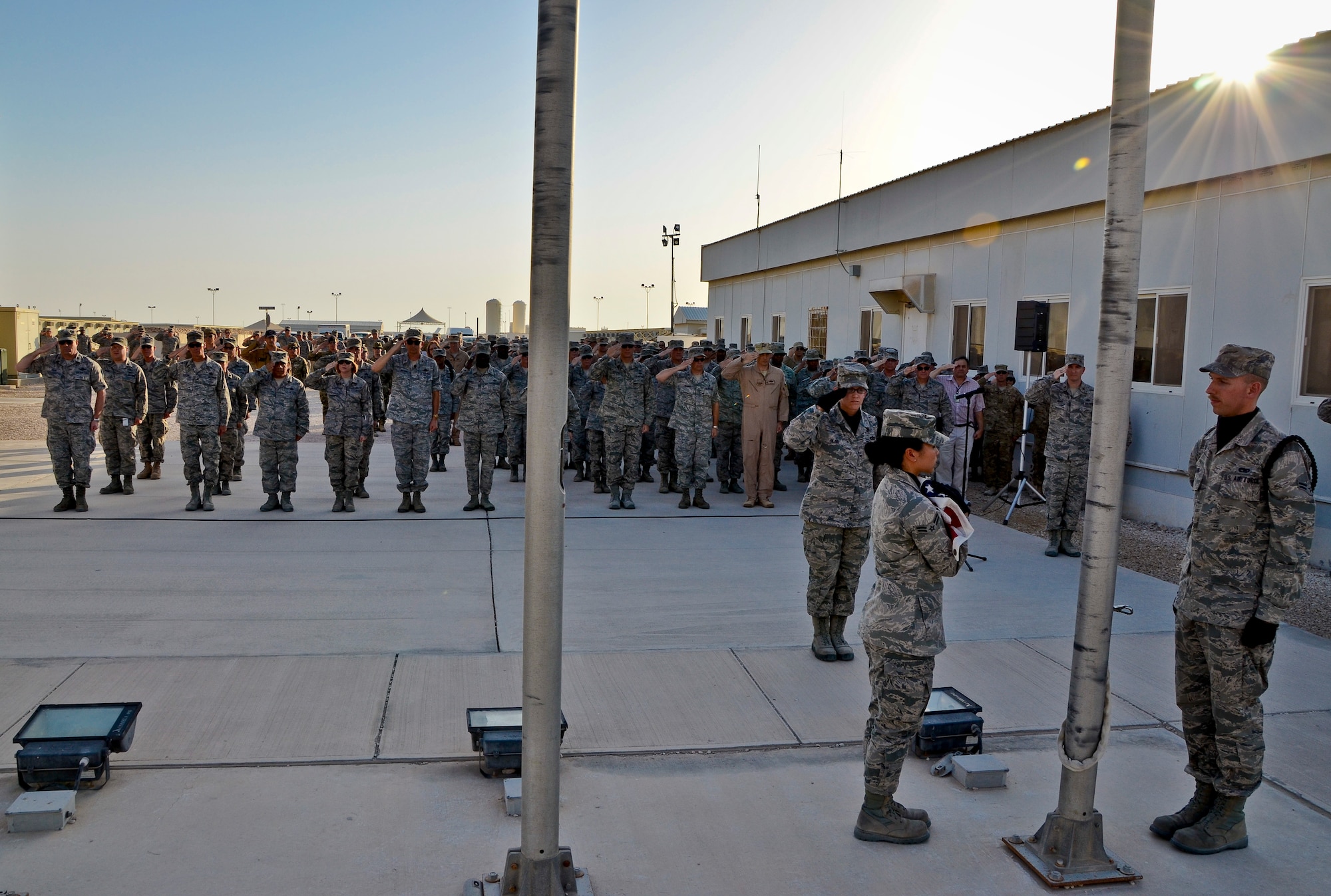 U.S. and coalition forces deployed to the 379th Air Expeditionary Wing salute the American flag during a Memorial Day retreat ceremony, May 27, 2013, at Memorial Plaza in Southwest Asia. Military retreat ceremonies serve a twofold purpose: to signal the end of the official duty day and to pay respect to the U.S. flag. (U.S. Air Force photo/Senior Airman Benjamin Stratton)