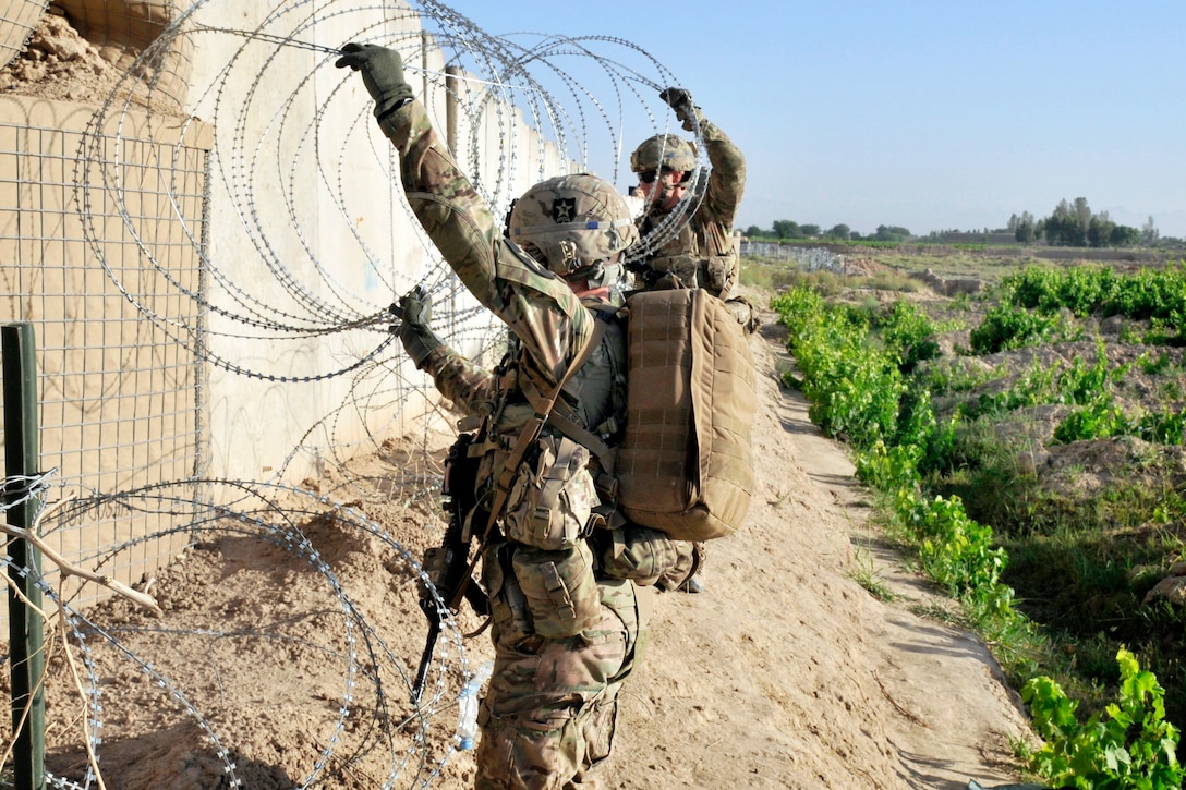 U.S. soldiers emplace concertina wire during a base defense patrol ...