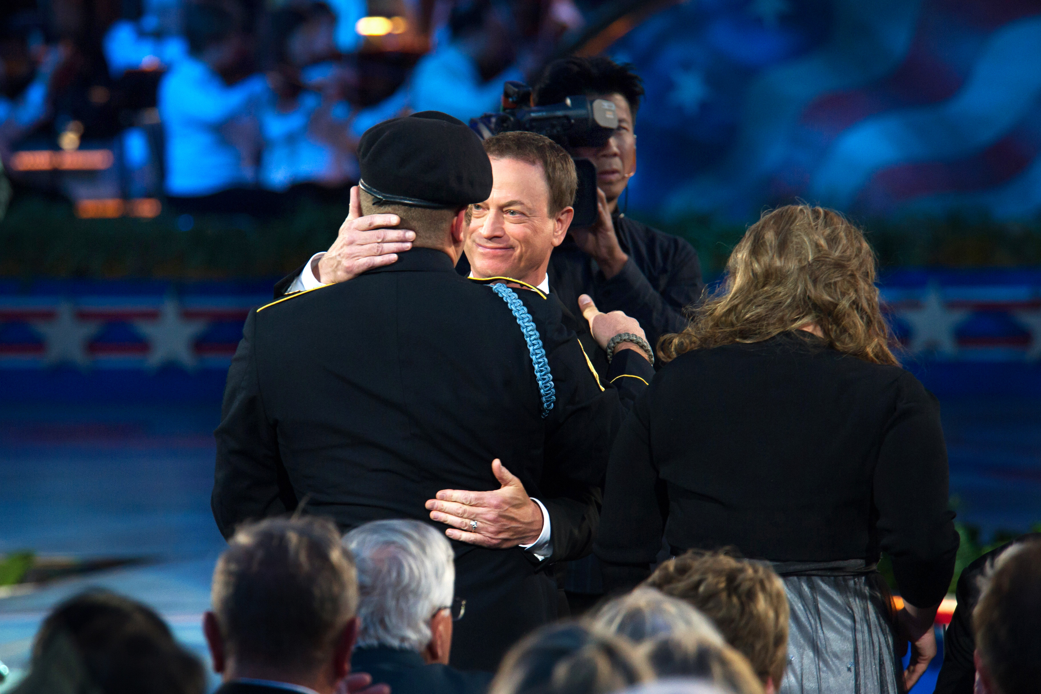 Actor and musician Gary Sinise hugs Army Staff Sgt. Earl Granville during  the National Memorial Day