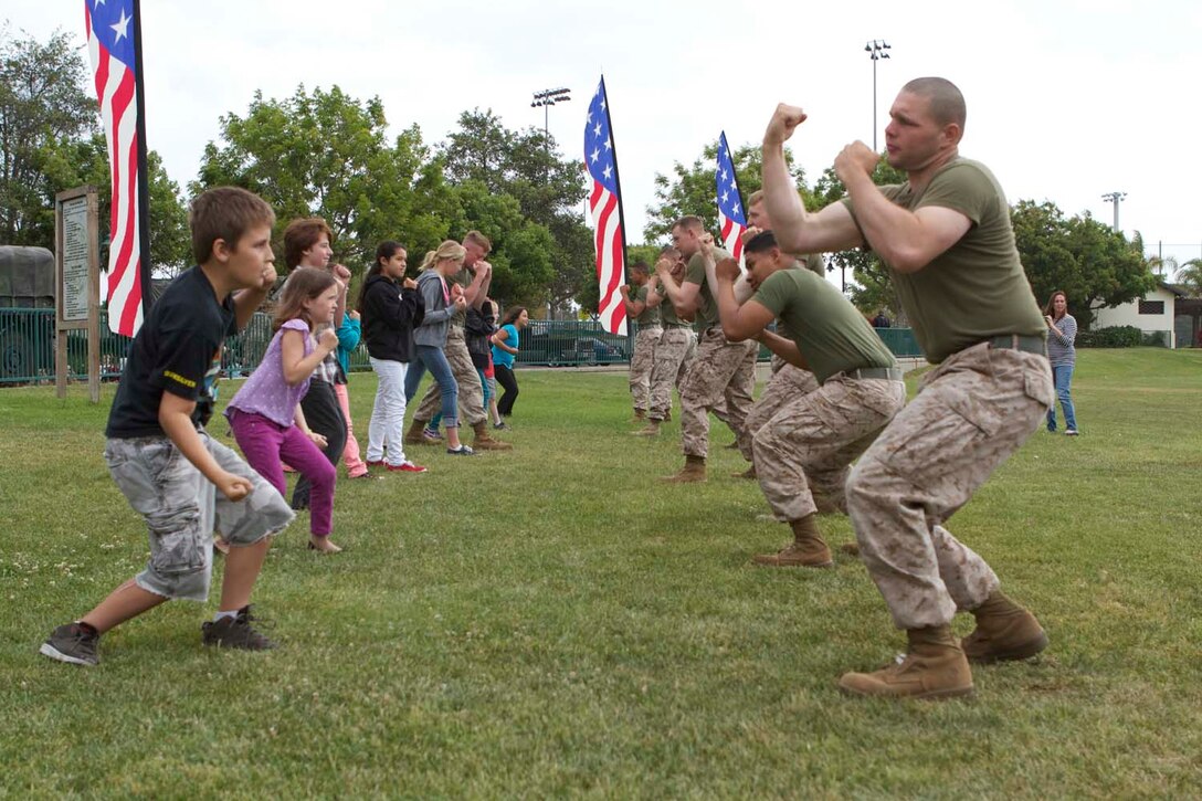 Marines serving with 1st Battalion, 11th Marine Regiment, show the children of San Juan Capistrano moves from the Marine Corps Martial Arts Program here, May 23, 2013. The children participated in several events set up by Marines including a combat fitness test. The Marines also participated in helping the citizens of San Juan Capistrano clean up their community and improve their community center.