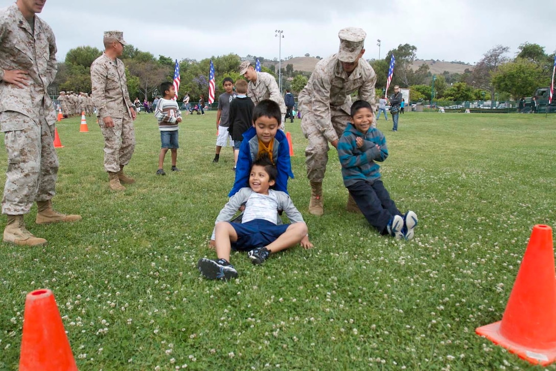 Marines serving with 1st Battalion, 11th Marine Regiment, show the children how to perform the combat fitness test here, May 23, 2013. There were more than 100 children participating in the event, giving them a taste of artilleryman life.The Marines also participated in helping the citizens of San Juan Capistrano clean up their community and beautify their community center.