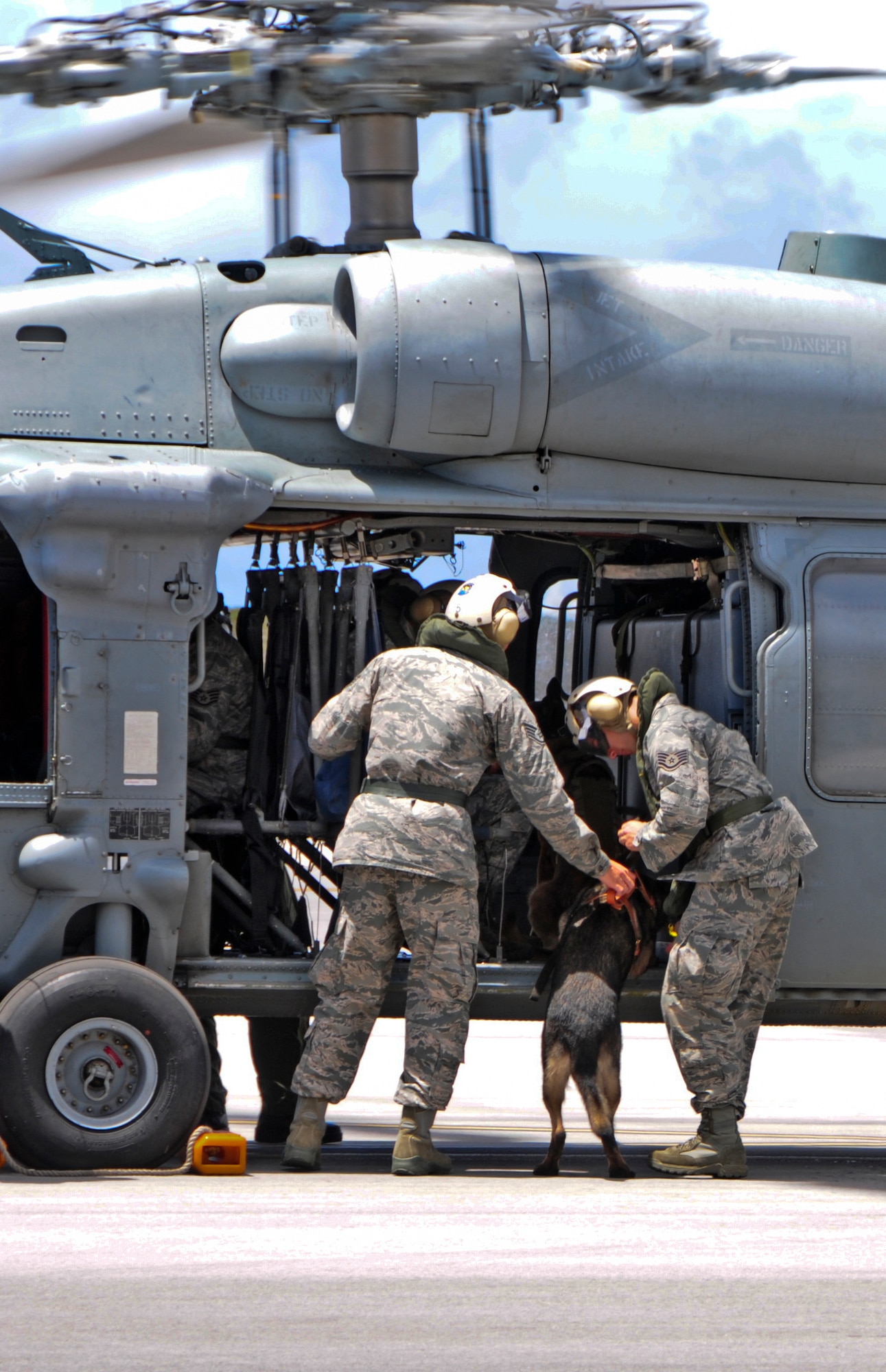 36th Security Forces Squadron military working dog handlers assist Viktor, 36th SFS MWD, on to an MH-60S Seahawk helicopter May 23, 2013, on Andersen Air Force Base, Guam. During helicopter familiarization training, MWD teams practice tactical deployment, air infiltration and exfiltration in order for MWDs to get used to going in and out of a moving helicopter. (U.S. Air Force photo by Airman 1st Class Marianique Santos/Released)