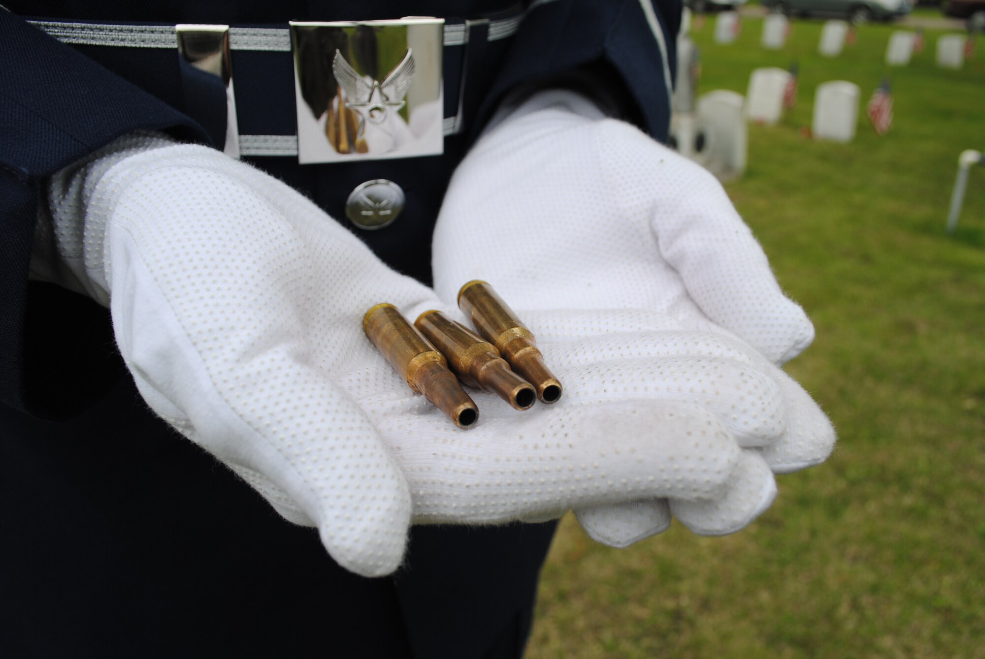 A member of the Grand Forks Air Force Base Honor Guard holds three brass bullet casings fired during a firing squad salute as part of a Memorial Day ceremony on May 24, 2013, at Memorial Park Cemetery in Grand Forks, N.D. The three casings represent the three rifle volleys fired in honor of the deceased service members. (U.S. Air Force photo/Staff Sgt. Luis Loza Gutierrez)
