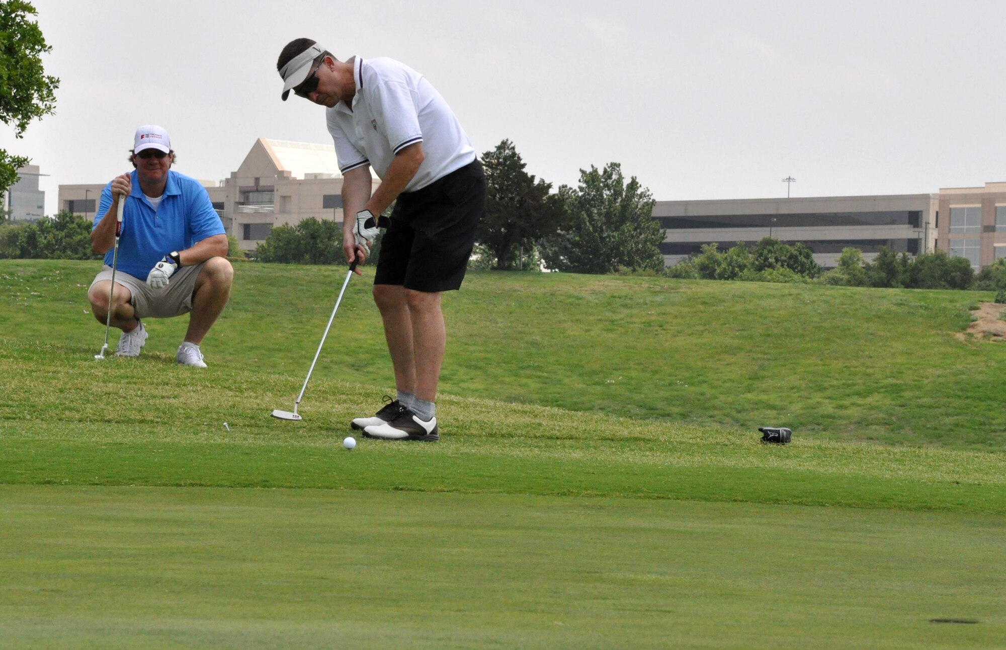 As one of his teammates watches, Navy CAPT Robert Bennett, Naval Air Station Fort Worth Joint Reserve Base installation commander, lines up a putt at the 16th hole during the Portraits of Patriotism Charity Golf Tournament recently. The tournament, held at Hackberry Creek Country Club in Irving, Texas, benefitted The American Fallen Soldiers Project, which helps provide comfort and healing to the mourning families of our fallen military men and women. (U.S. Air Force photo/Master Sgt. Julie Briden-Garcia)
