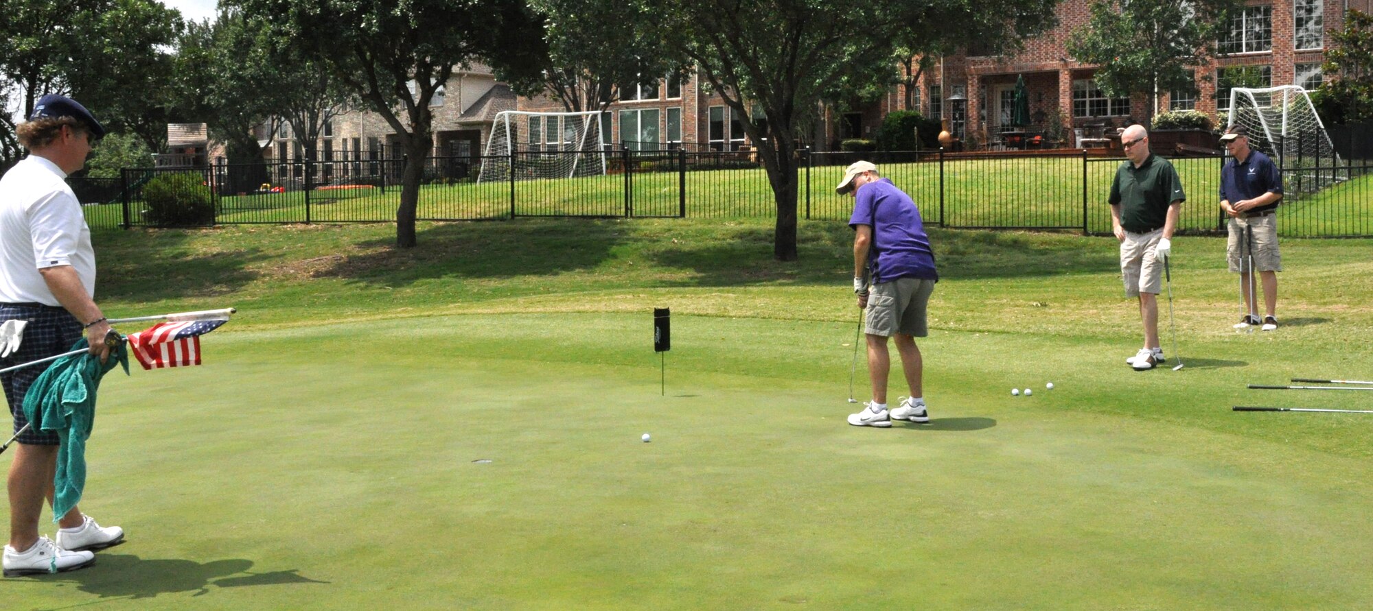 As the rest of his team watches, Army Maj. James Sisk, commander of the 339th Military Intellengence Company, 11th Aviation Command, sinks a putt at the 8th hole during the Portraits of Patriotism Charity Golf Tournament recently. The tournament, held at Hackberry Creek Country Club in Irving, Texas, benefitted The American Fallen Soldiers Project, which helps provide comfort and healing to the mourning families of our fallen military men and women. (U.S. Air Force photo/Master Sgt. Julie Briden-Garcia)